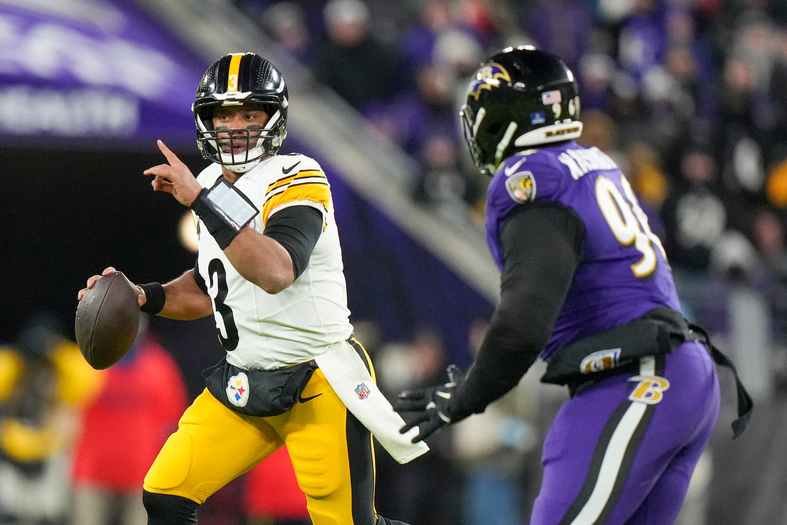 Pittsburgh Steelers quarterback Russell Wilson, left, gestures while scrambling against Baltimore Ravens defensive tackle Broderick Washington during the first half of an NFL football game, Saturday, Dec. 21, 2024, in Baltimore. (AP Photo/Stephanie Scarbrough)