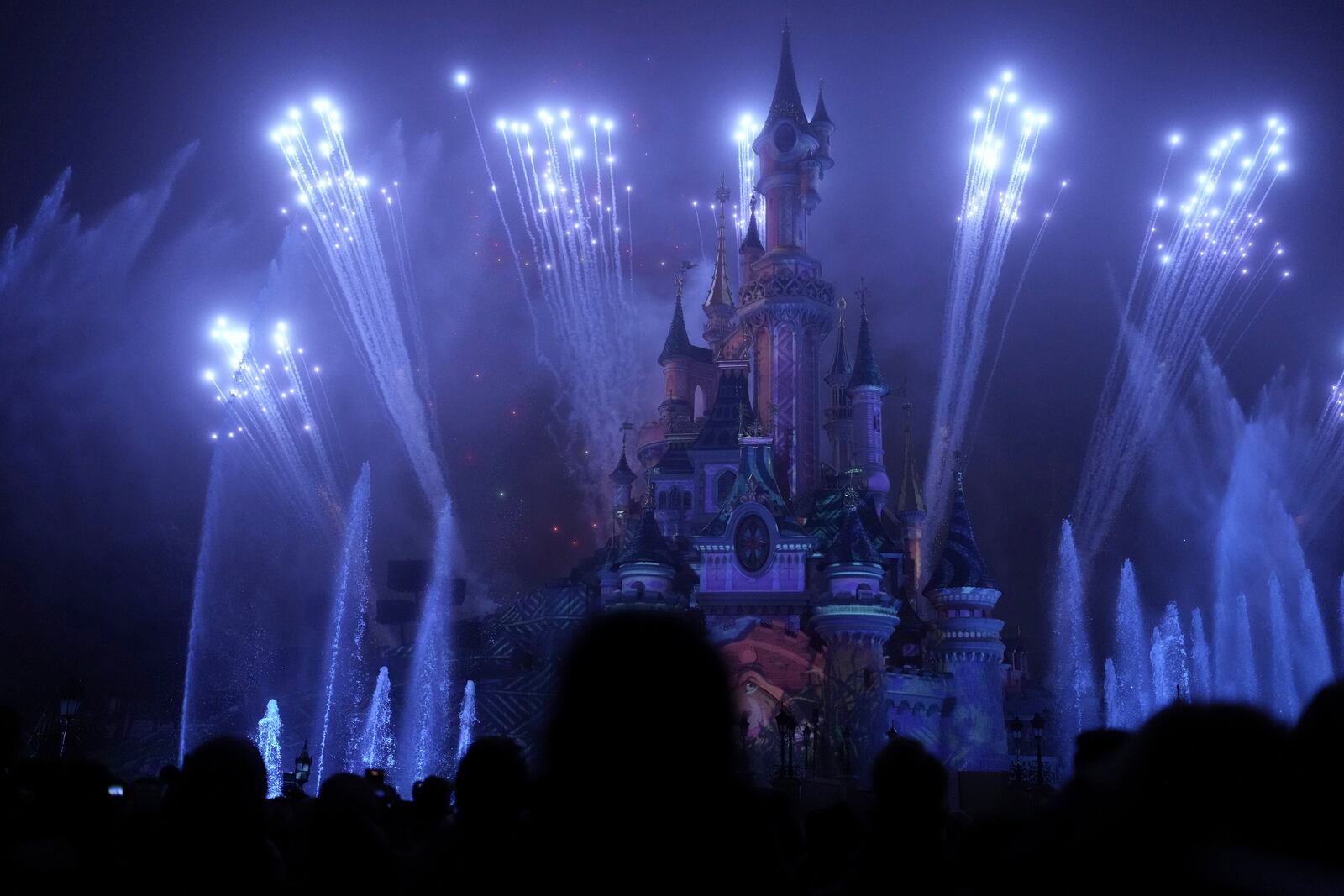 A light show is projected on the castle of Sleeping Beauty as fireworks explode in Disneyland, in Marne-la-Vallee, east of Paris, Friday Jan. 17, 2025. (AP Photo/Thibault Camus)