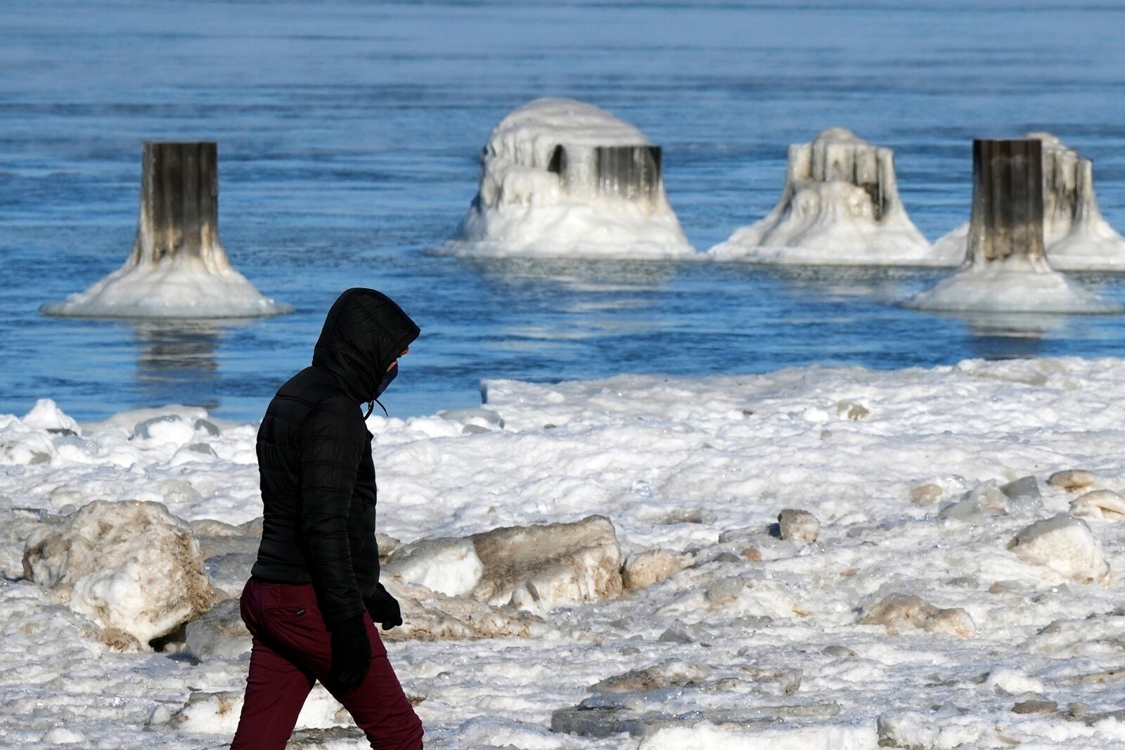 A man bundles up as he walks along the shore of snow-covered Lake Michigan during a cold day in Chicago, Tuesday, Jan. 21, 2025. (AP Photo/Nam Y. Huh)