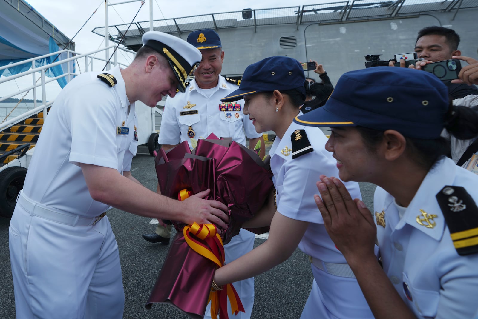 Daniel A. Sledz, left, commanding officer of USS Savannah, receives a bouquet of flowers from Cambodian naval staff members as it arrives for a port call at Sihanoukville port, Cambodia, Monday, Dec. 16, 2024. (AP Photo/Heng Sinith)