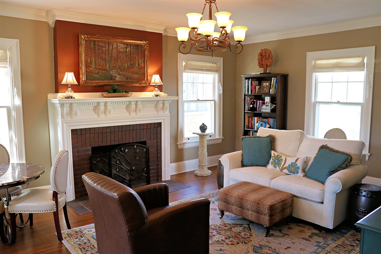 The centerpiece to the living room is a brick fireplace with a dentil wood mantel and tile hearth. Large windows flank the fireplace and are framed by white bold molding, which match the double-crown molding. 