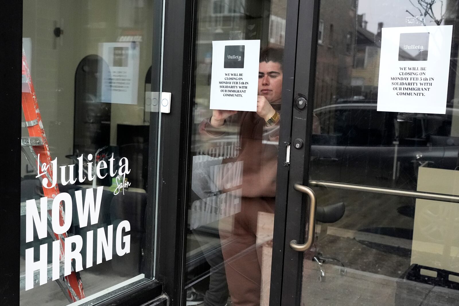 Andrea Toro, owner of La Julieta Salon, tapes a closure sign on her store in the Pilsen neighborhood of Chicago to stand with immigrants, in Chicago, Monday, Feb. 3, 2025. (AP Photo/Nam Y. Huh)