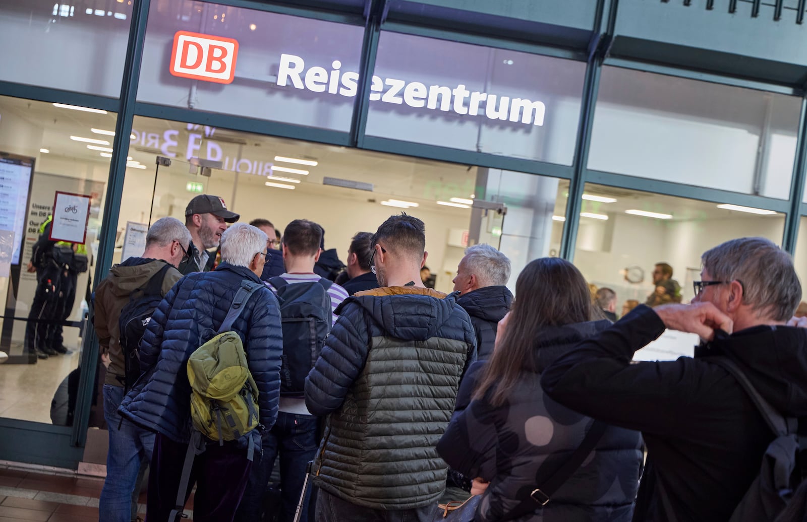 A queue of people forms in front of the travel center at the main station, after all flights at Hamburg Airport are canceled due to strikes, in Hamburg, Germany, Sunday, March 9, 2025. (Georg Wendt/dpa via AP)