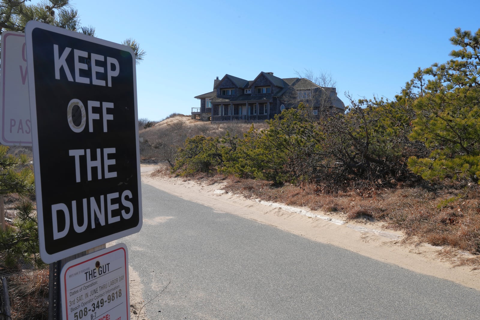 A sign in front of a home that sits atop a sandy bluff reads "keep off the dunes", in Wellfleet, Mass., Monday, Jan. 27, 2025. (AP Photo/Andre Muggiati)