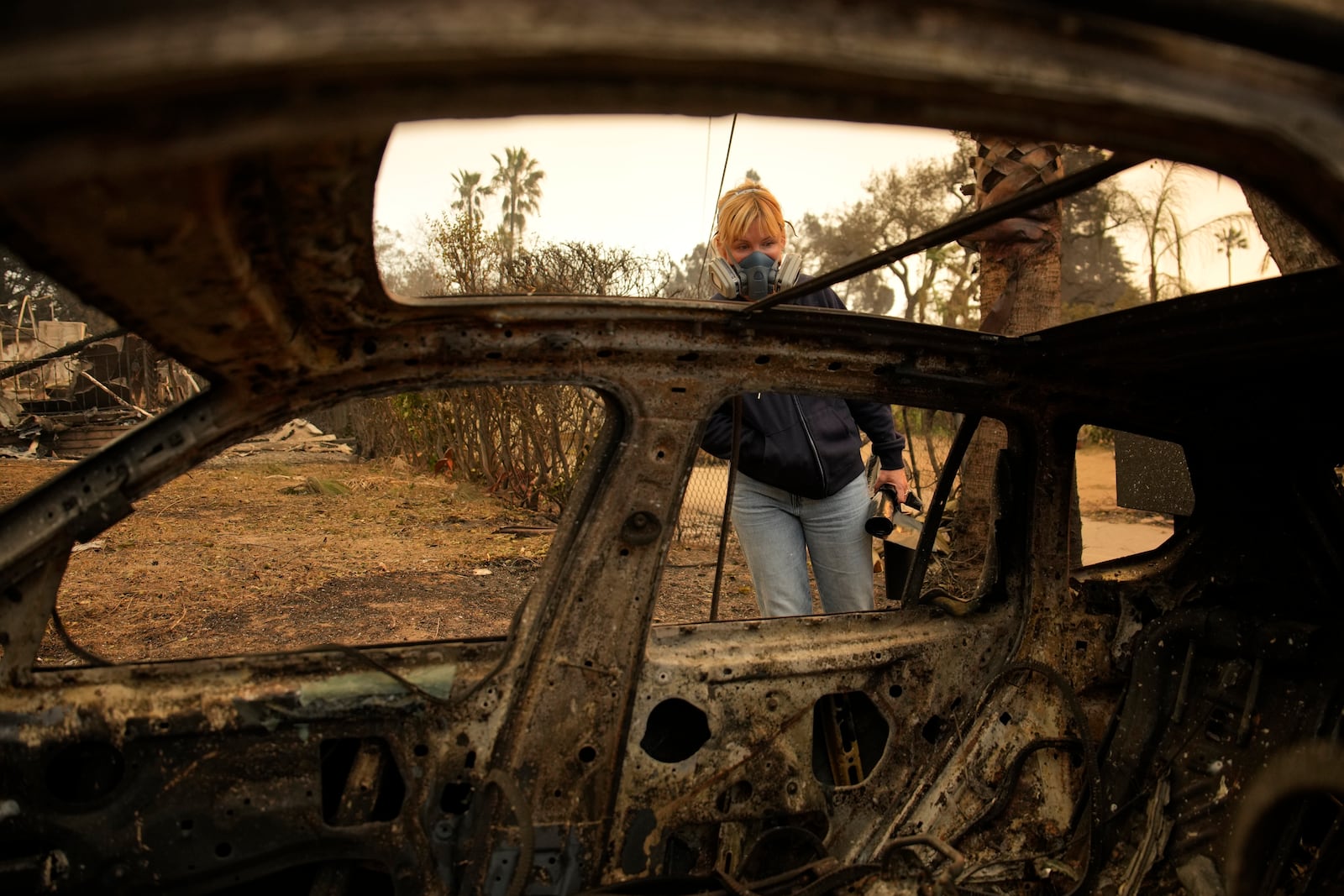 Lisa Renn looks at remains of car in Altadena, Calif., Thursday, Jan. 9, 2025. (AP Photo/John Locher)