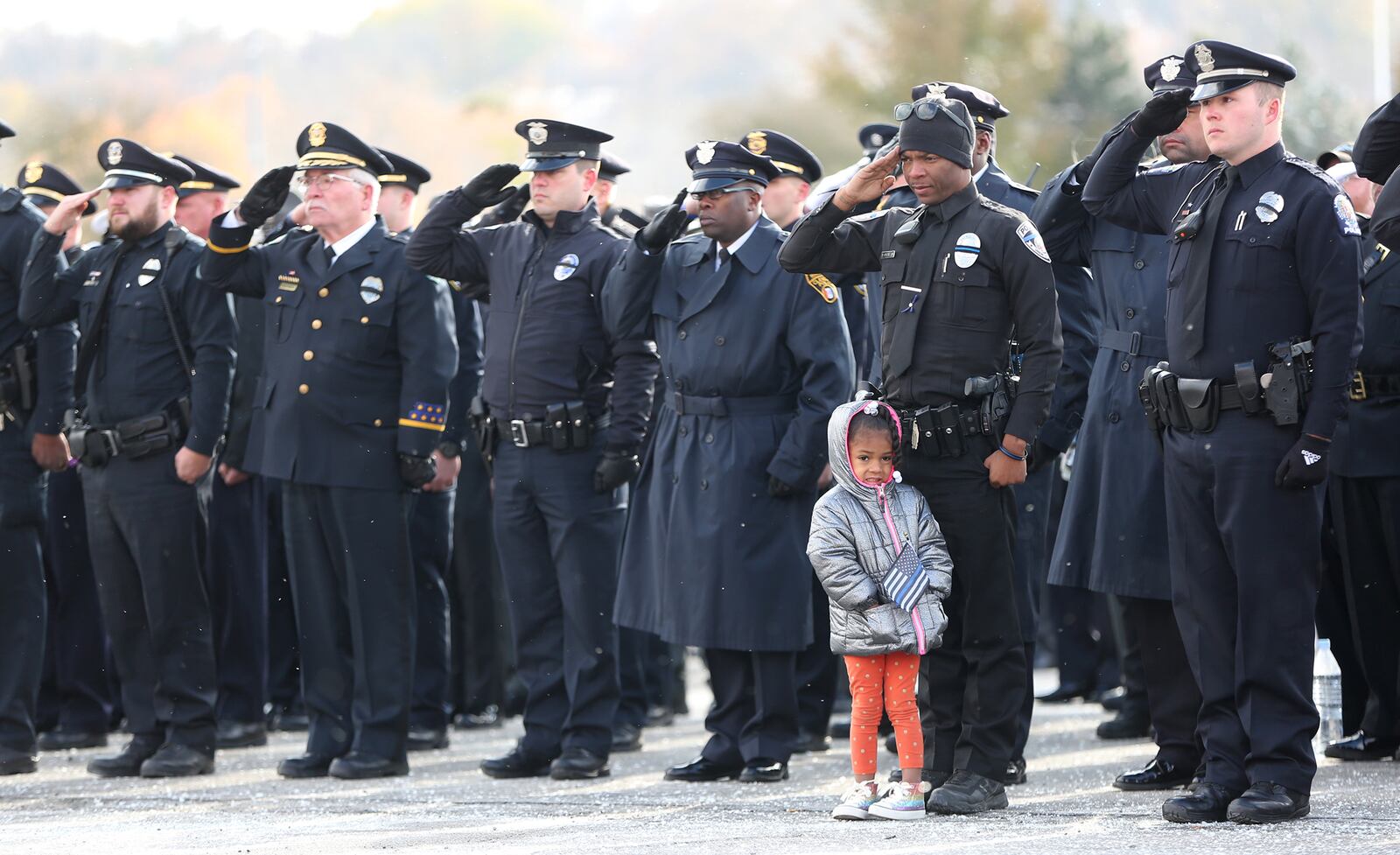 Union City Patrol Officer Darnell Pate brought his daughter, Bra'Lynn Pate to the funeral services for Dayton police detective Jorge DelRio Nov. 12. LISA POWELL / STAFF