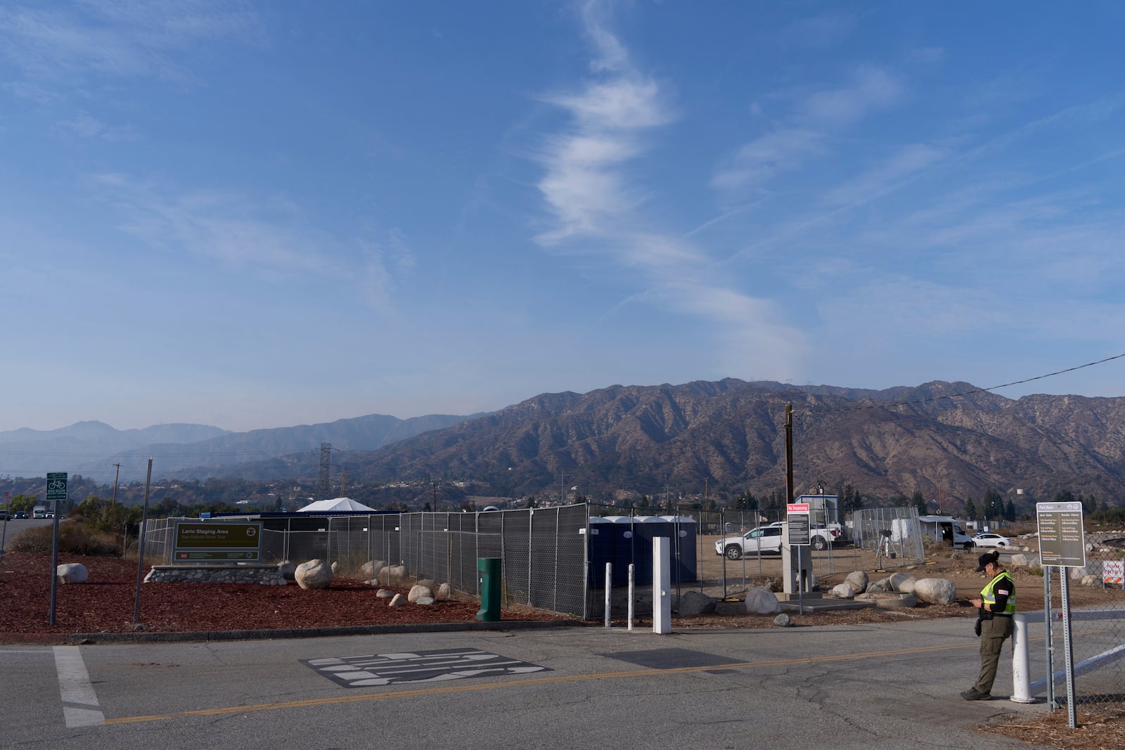 An official guards the fenced Lario Park, used by the U.S. Environmental Protection Agency (EPA) temporarily for processing hazardous materials from the Eaton Fire, in Irwindale, Calif., Friday, Jan. 31, 2025. (AP Photo/Damian Dovarganes)