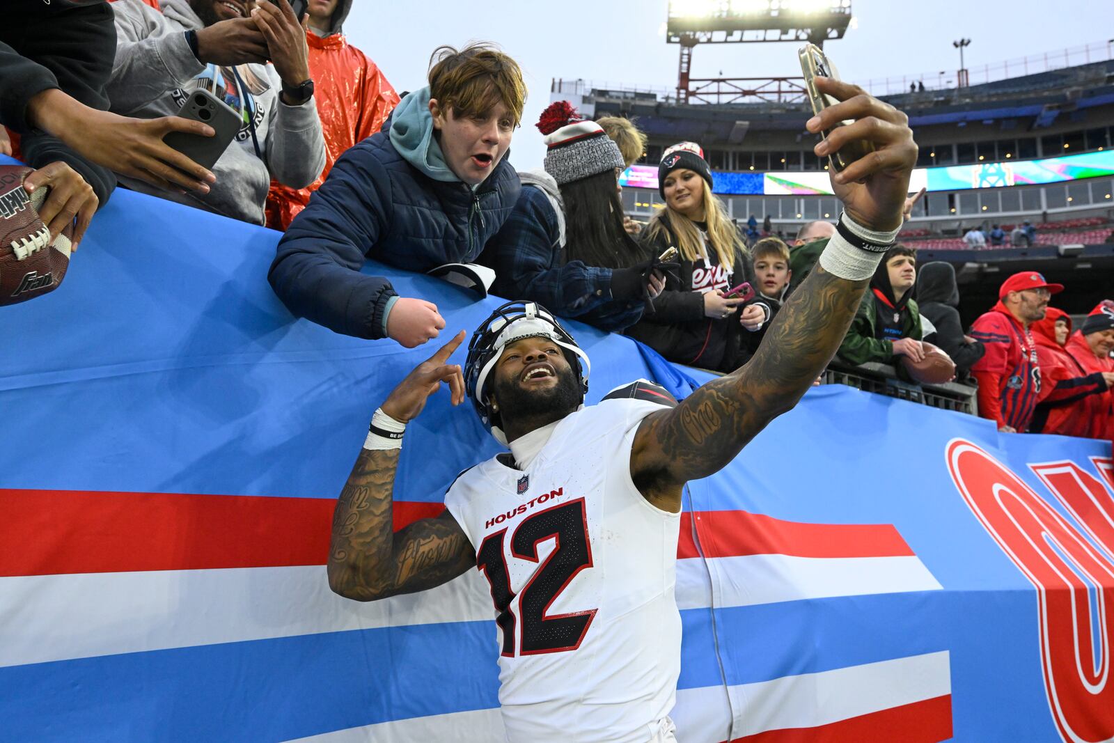 Houston Texans wide receiver Nico Collins (12) celebrates with a fan after an NFL football game against the Tennessee Titans Sunday, Jan. 5, 2025, in Nashville, Tenn. The Texans won 23-14. (AP Photo/John Amis)