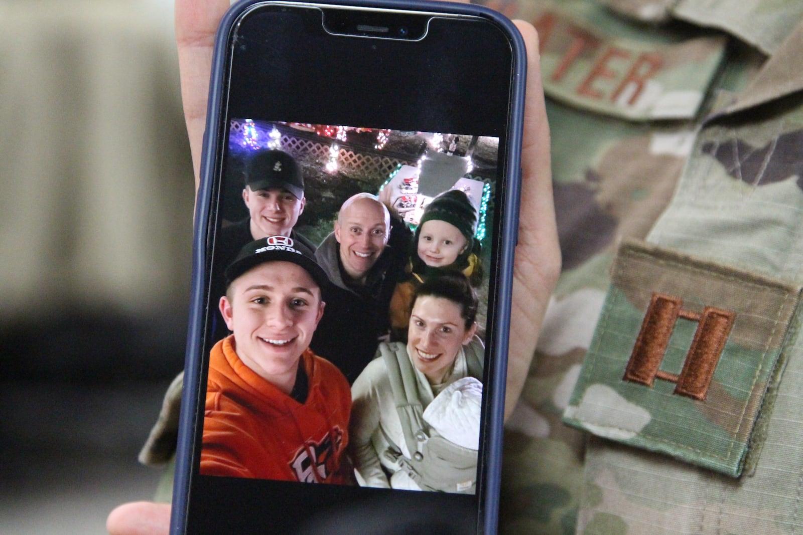 Capt., Courtney Slater, with the Ohio Air National Guard, holds up a picture of her family, including her husband Danny, a pilot and part time guard member who is currently on alert, meaning that he could potentially be deployed to where ever he is needed. Hasan Karim/Staff