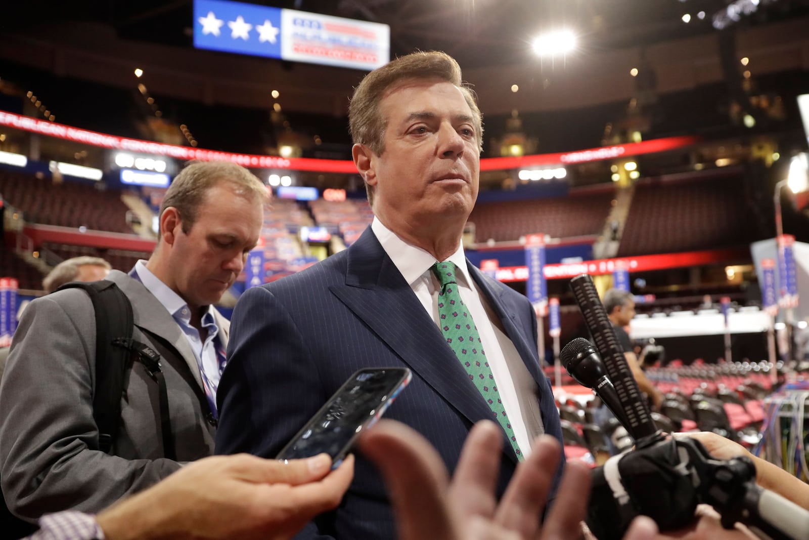 Manafort talks to reporters on the floor of the Republican National Convention at Quicken Loans Arena in Cleveland as Rick Gates listens at back left on July 17, 2016.