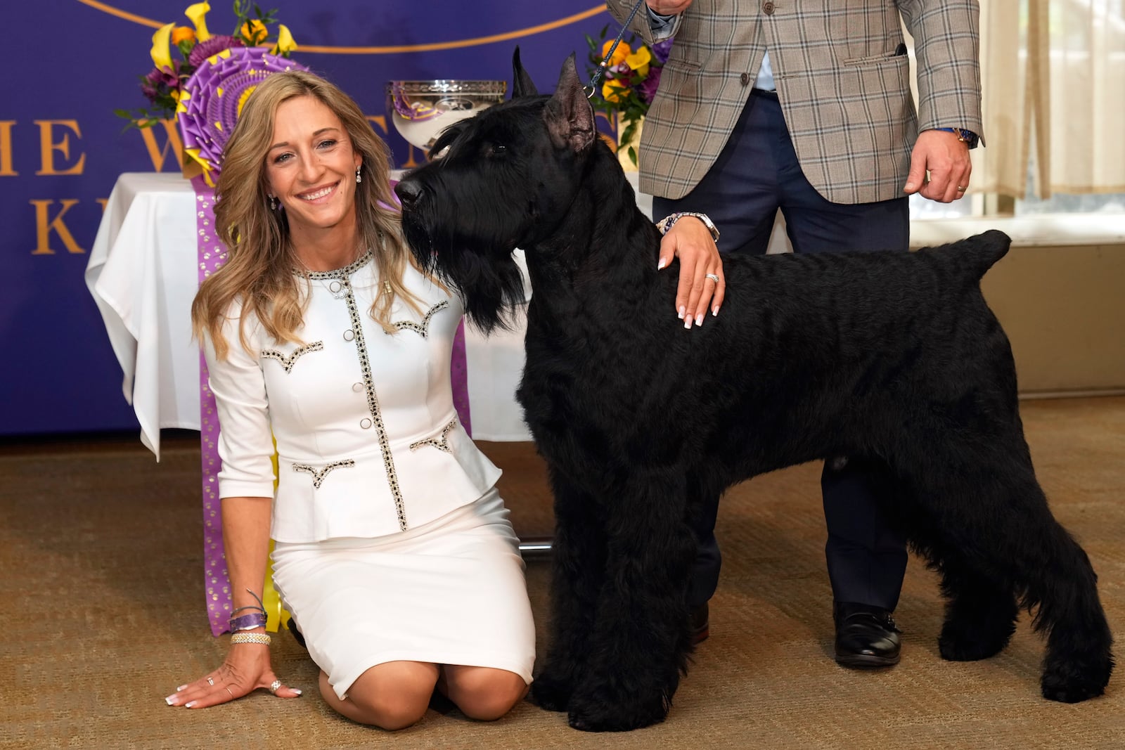 Handler and co-owner Katie Bernardin poses with Monty, a giant schnauzer, before he is treated to the Champion's Lunch at Bar Boulud, in New York, Wednesday, Feb. 12, 2025, after winning best in show at the 149th Westminster Kennel Club dog show. (AP Photo/Richard Drew)