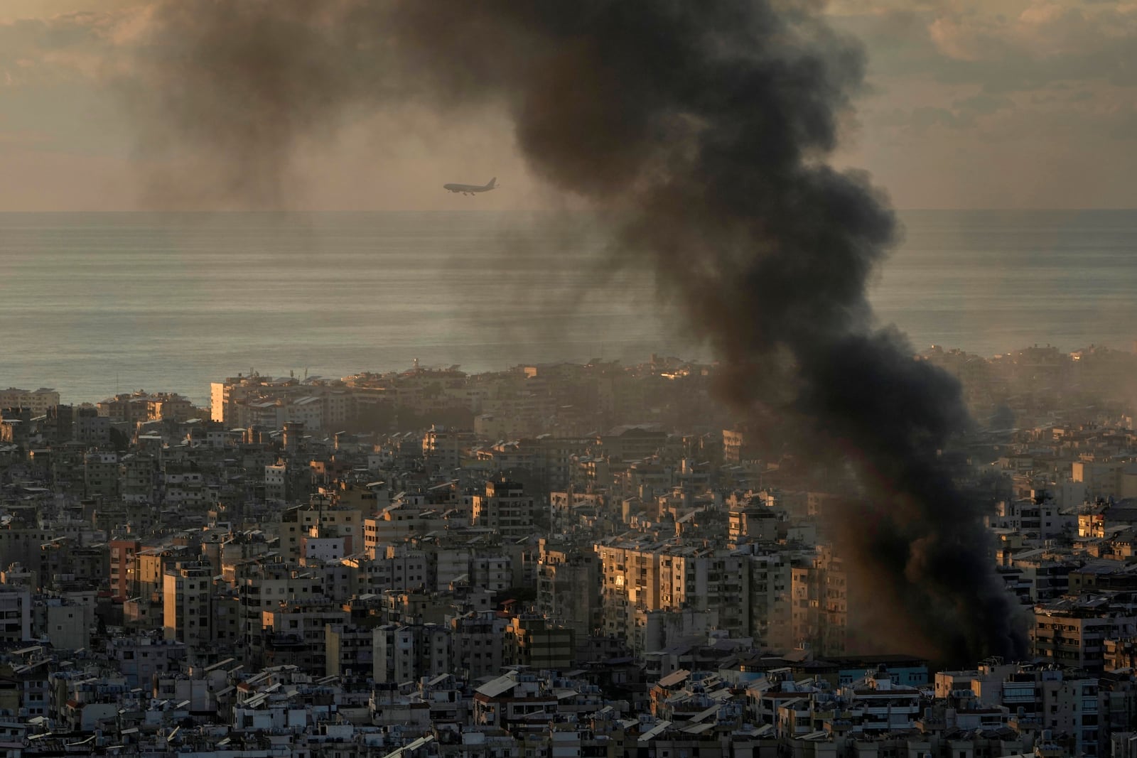 A Middle East Airlines plane flies as smoke rises following an Israeli airstrike on Dahiyeh, in Beirut, Lebanon, Tuesday, Nov. 26, 2024. (AP Photo/Bilal Hussein)