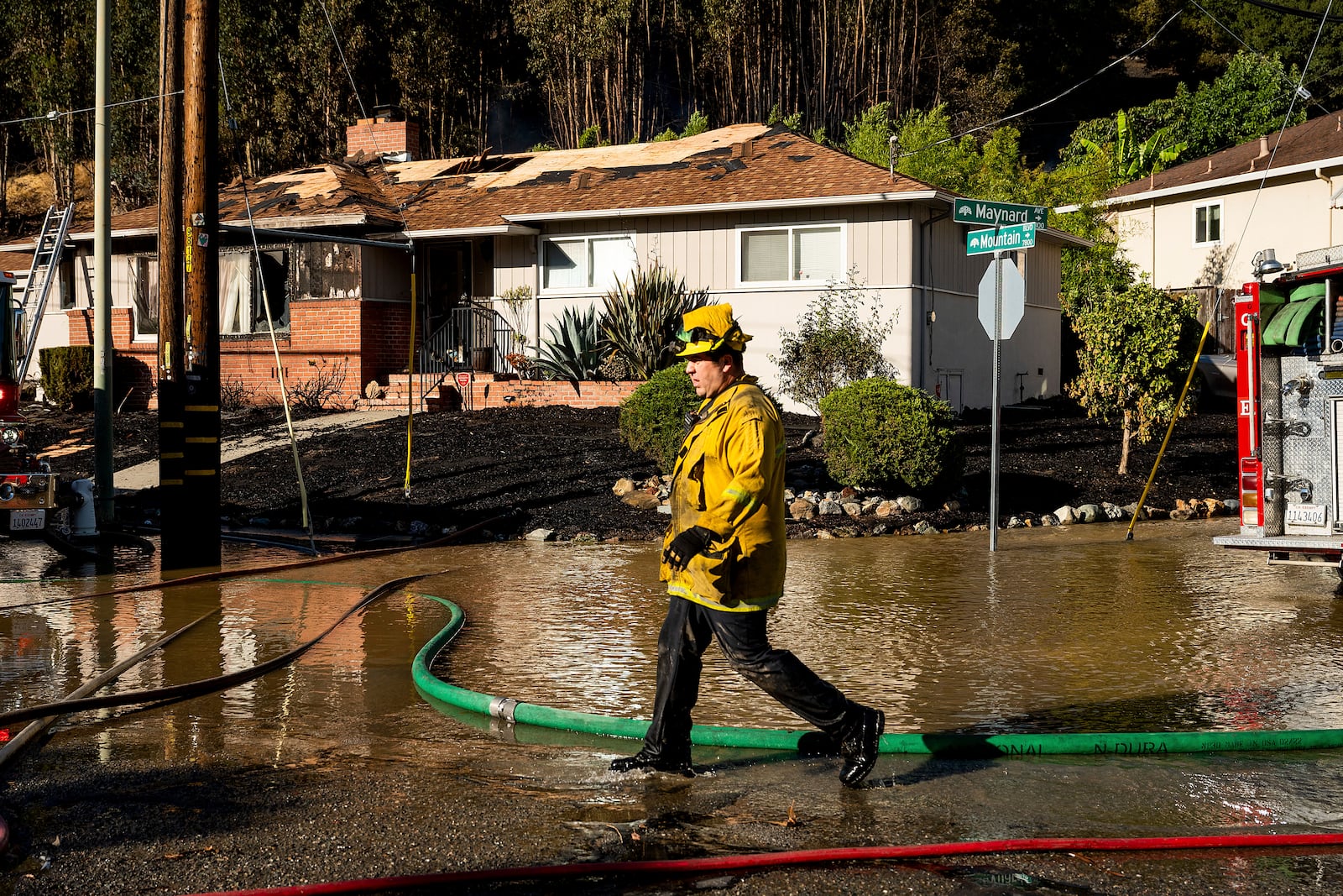 A firefighter passes a home scorched in the Keller Fire near Interstate 580 in Oakland, Calif.,on Friday, Oct. 18, 2024. (AP Photo/Noah Berger)