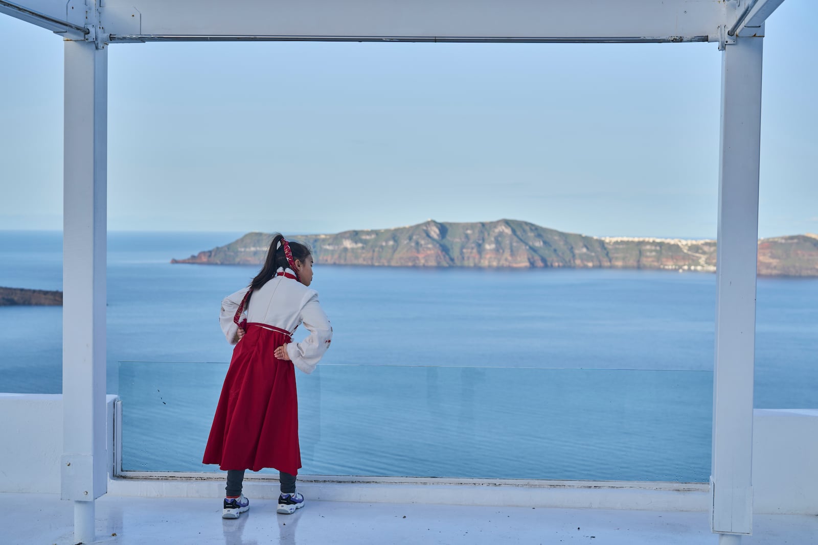 A woman from China looks on from a caldera at Firostefani, as in the background stands the island of Therasia, while authorities are taking emergency measures in response to intense seismic activity on the popular Aegean Sea holiday island of Santorini, southern Greece, Tuesday, Feb. 4, 2025. (AP Photo/Petros Giannakouris)