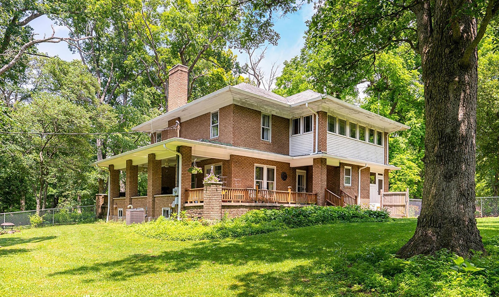 A wood-paneled, second-floor sunroom features walls of windows. It has wood floors and exposed brick. On the first floor a wood exterior door in a potential office room opens to the covered side porch. CONTRIBUTED PHOTO