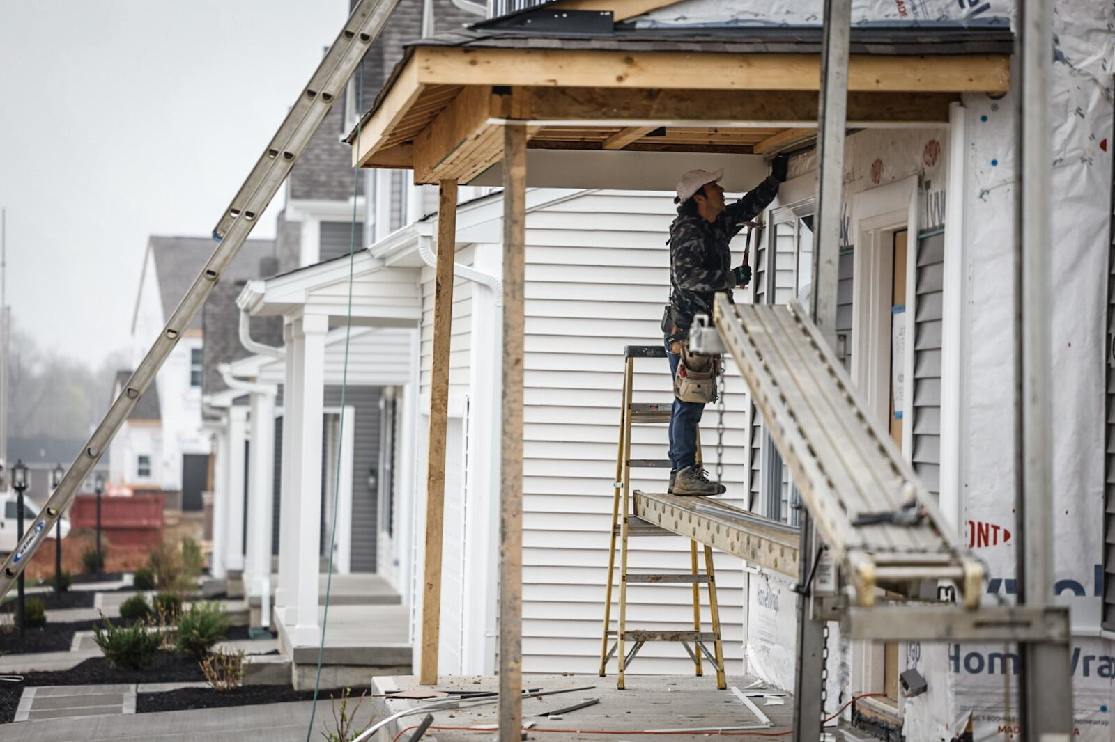 Nestor Uzhca hangs siding on a newly constructed house on Chamberlin Drive in Miamisburg Wednesday, April 10, 2024. Total new permits pulled for 2023 numbered 1,697, down 14.8% from 2022, according to Home Builders Association of Dayton. JIM NOELKER/STAFF