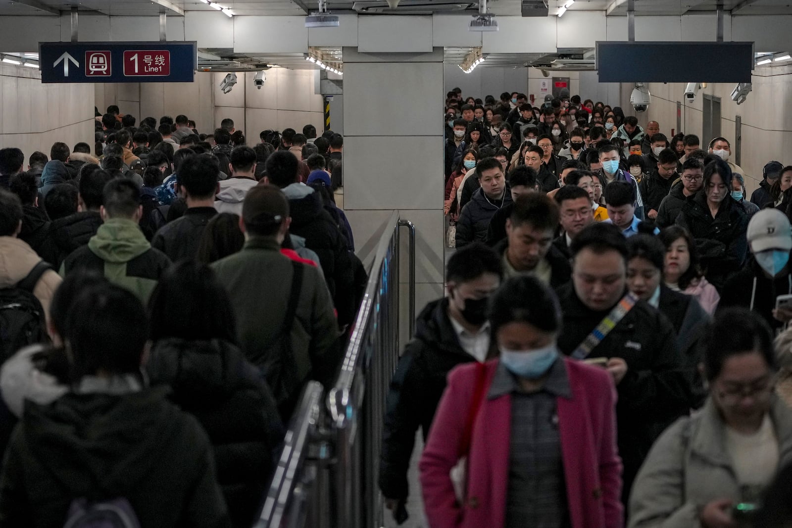 Commuters walk through a walkway in between two subway stations as they head to work during the morning rush hour in Beijing, Thursday, March 6, 2025. (AP Photo/Andy Wong)