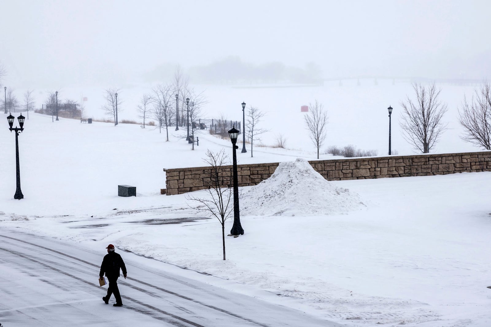 A person walks across the street as a snowstorm rolls in, Wednesday, Feb. 12, 2025 in Uptown Bay City, Mich. (Kaytie Boomer/The Bay City Times via AP)