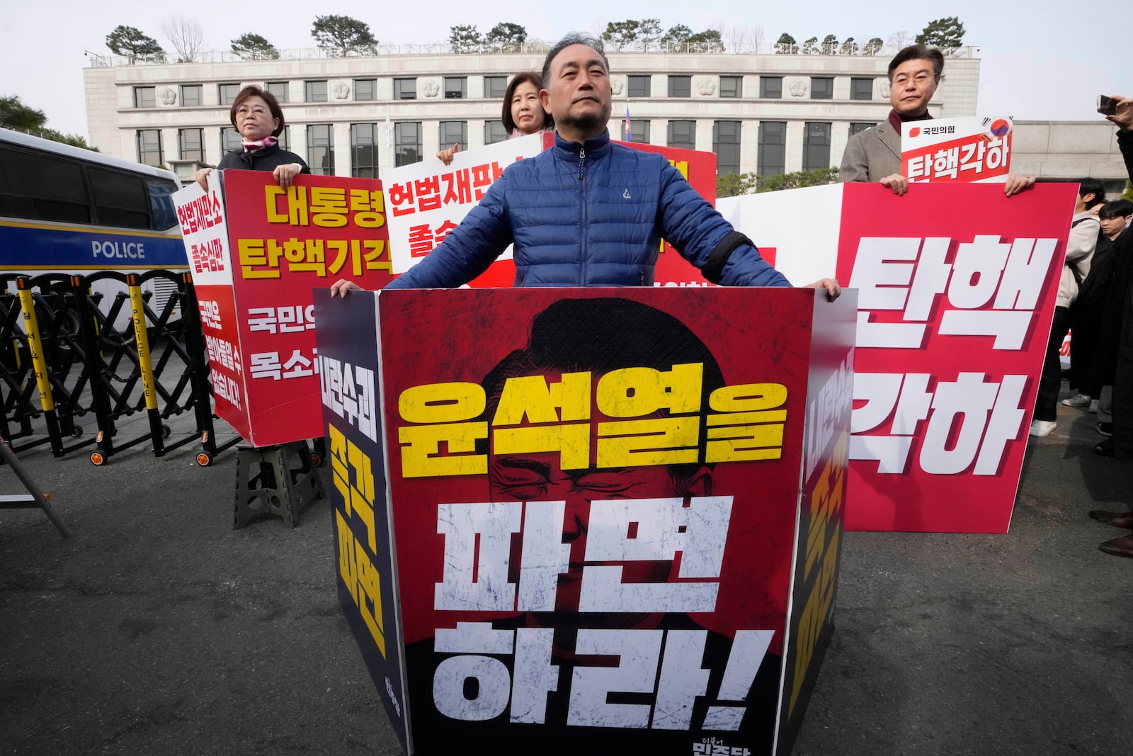 A member of the main opposition Democratic Party, front, and members of the ruling People Power Party stand in front of the Constitutional Court in Seoul, South Korea, Monday, March 24, 2025. The banners read "Dismiss Yoon Suk Yeol," front, and "Dismiss impeachment." (AP Photo/Ahn Young-joon)