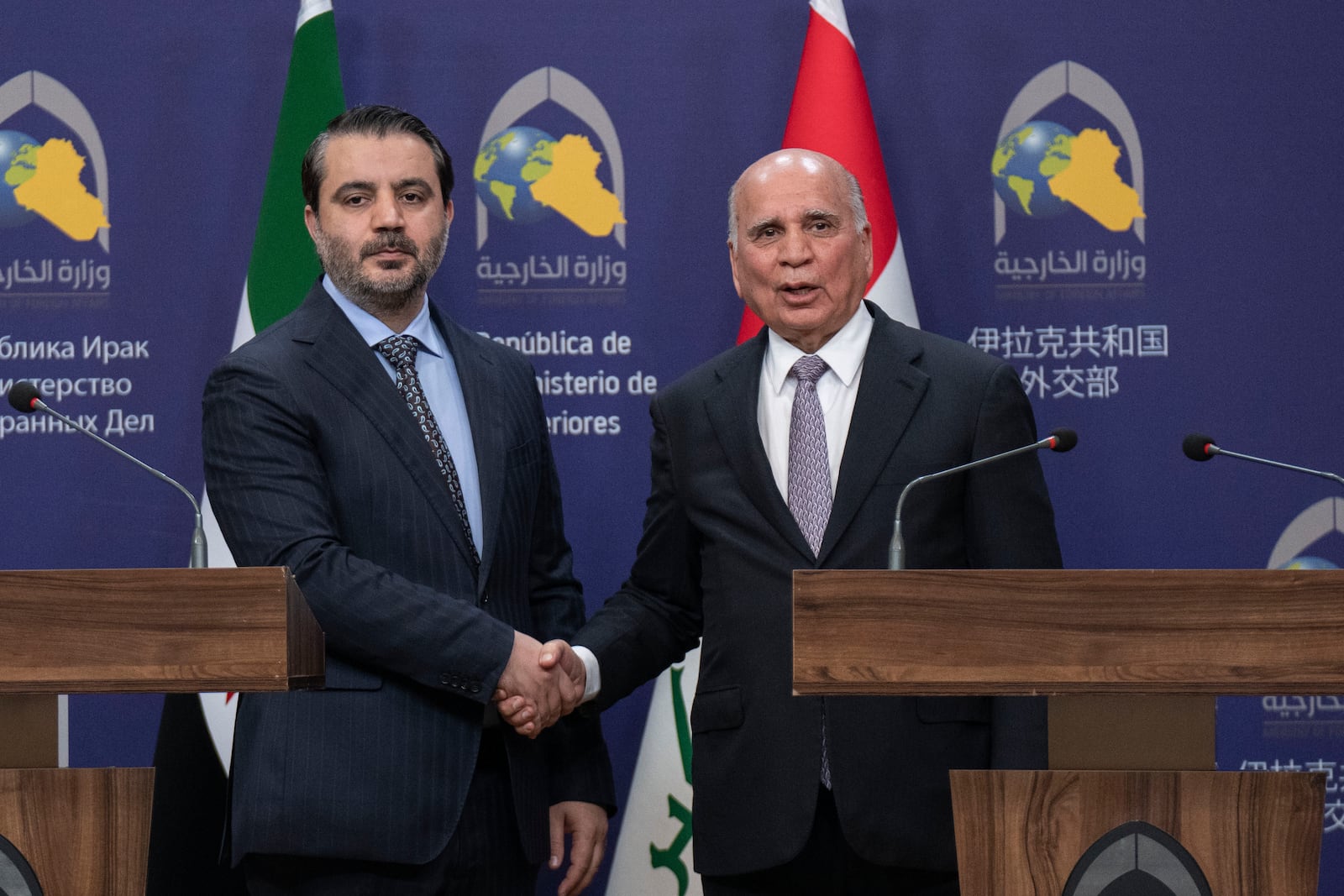 Iraqi Foreign Minister Fouad Hussein, right, shakes hands with Syrian Foreign Minister Asaad al-Shaybani, left, in Baghdad, Iraq, Friday, March.14, 2025. (AP Photo/Hadi Mizban)