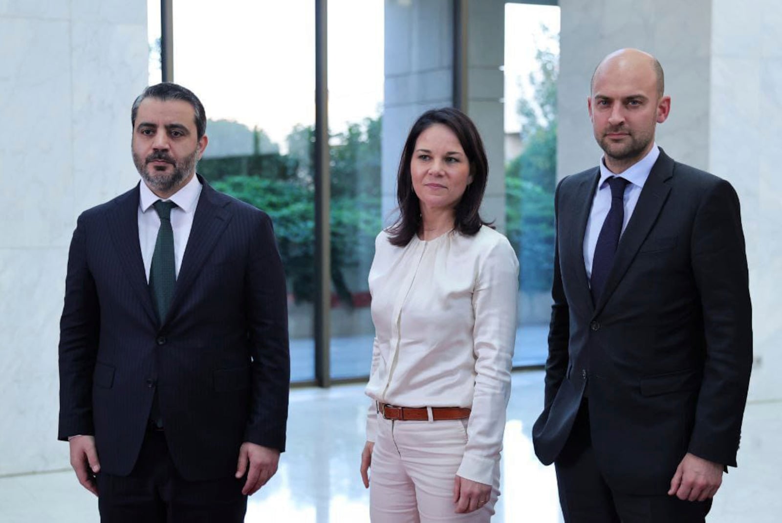 In this photo released by the Syrian official news agency SANA, Syria's Foreign Minister Asaad al-Shibani, left, stands with his German counterpart, Annalena Baerbock, center, and his French counterpart, Jean-Noel Barrot, in Damascus, Syria, Friday, Jan. 3, 2025. (SANA via AP)