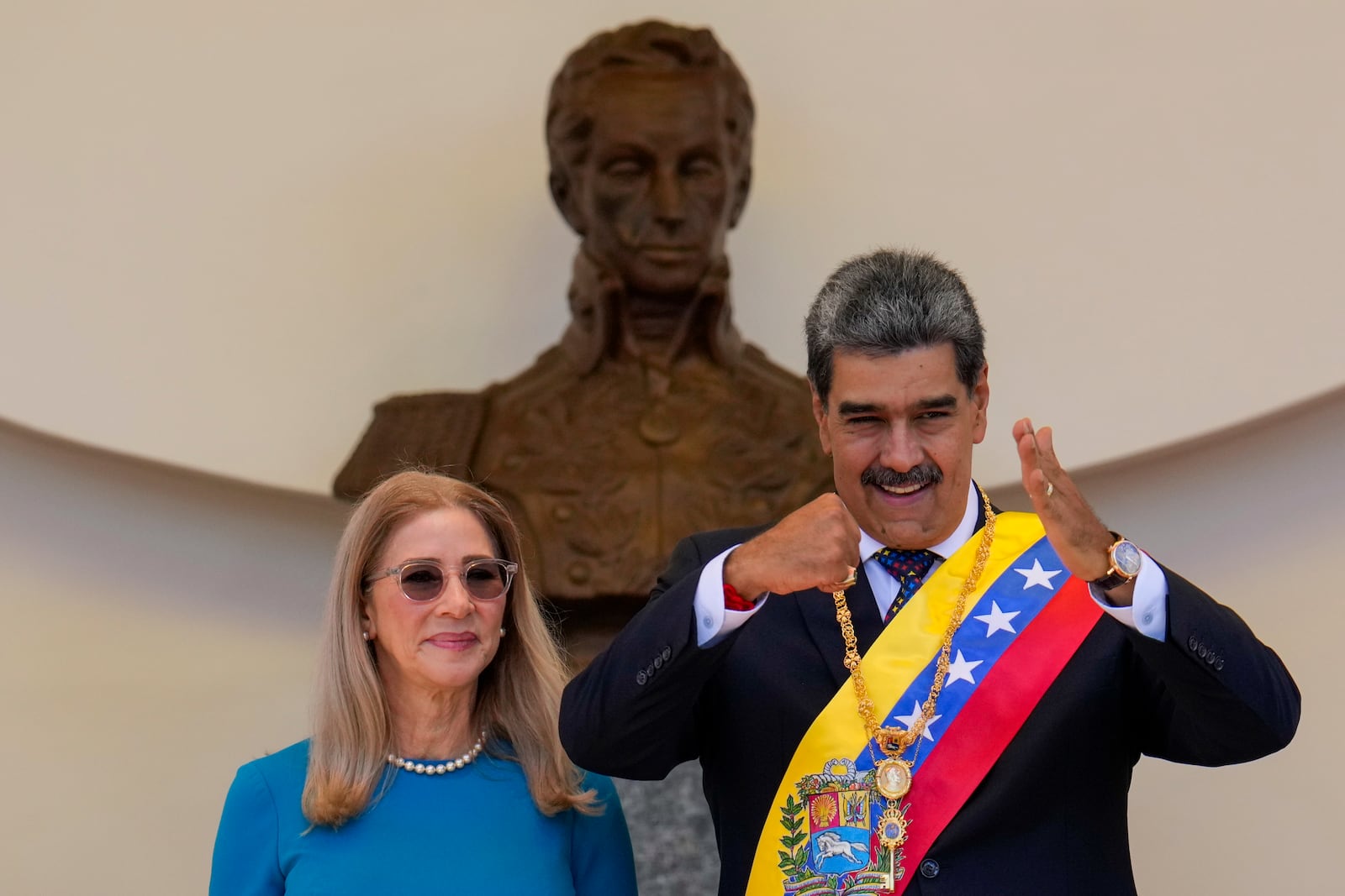 Venezuelan President Nicolas Maduro gestures to supporters next to his wife Cilia Flores after his swearing-in ceremony for a third term in Caracas, Venezuela, Friday, Jan. 10, 2025. (AP Photo/Ariana Cubillos)