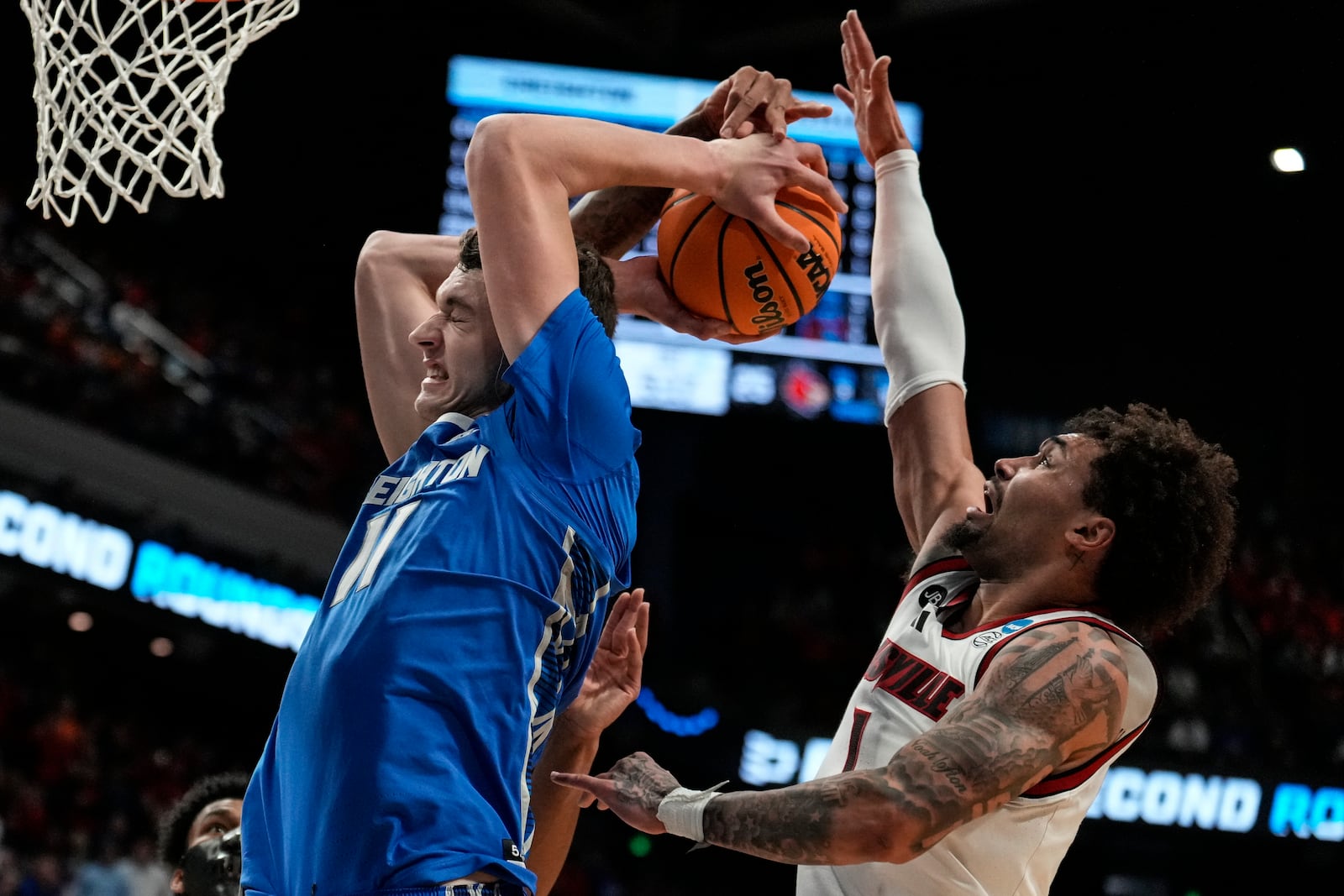 Creighton center Ryan Kalkbrenner (11) moves the basket against Louisville guard J'Vonne Hadley (1) during the first half in the first round of the NCAA college basketball tournament, Thursday, March 20, 2025, in Lexington, Ky. (AP Photo/Brynn Anderson)