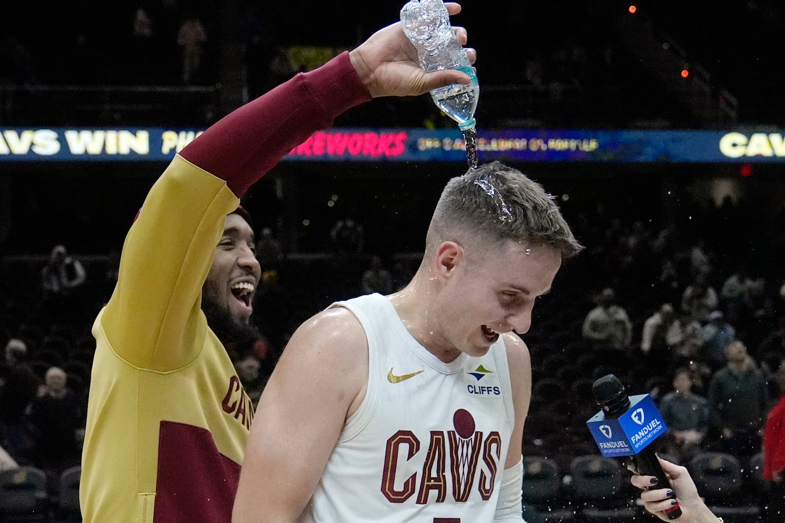 Cleveland Cavaliers guard Sam Merrill, right, is doused with water by teammate Donovan Mitchell, left, during an on-court interview after an NBA basketball game against the Dallas Mavericks, Sunday, Feb. 2, 2025, in Cleveland. (AP Photo/Sue Ogrocki)