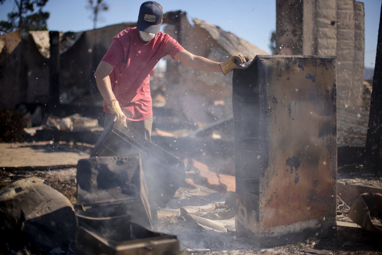 Todd Howard sifts through the remains of his parents' fire-ravaged property after the Mountain Fire swept through, Thursday, Nov. 7, 2024, in Camarillo, Calif. (AP Photo/Ethan Swope)