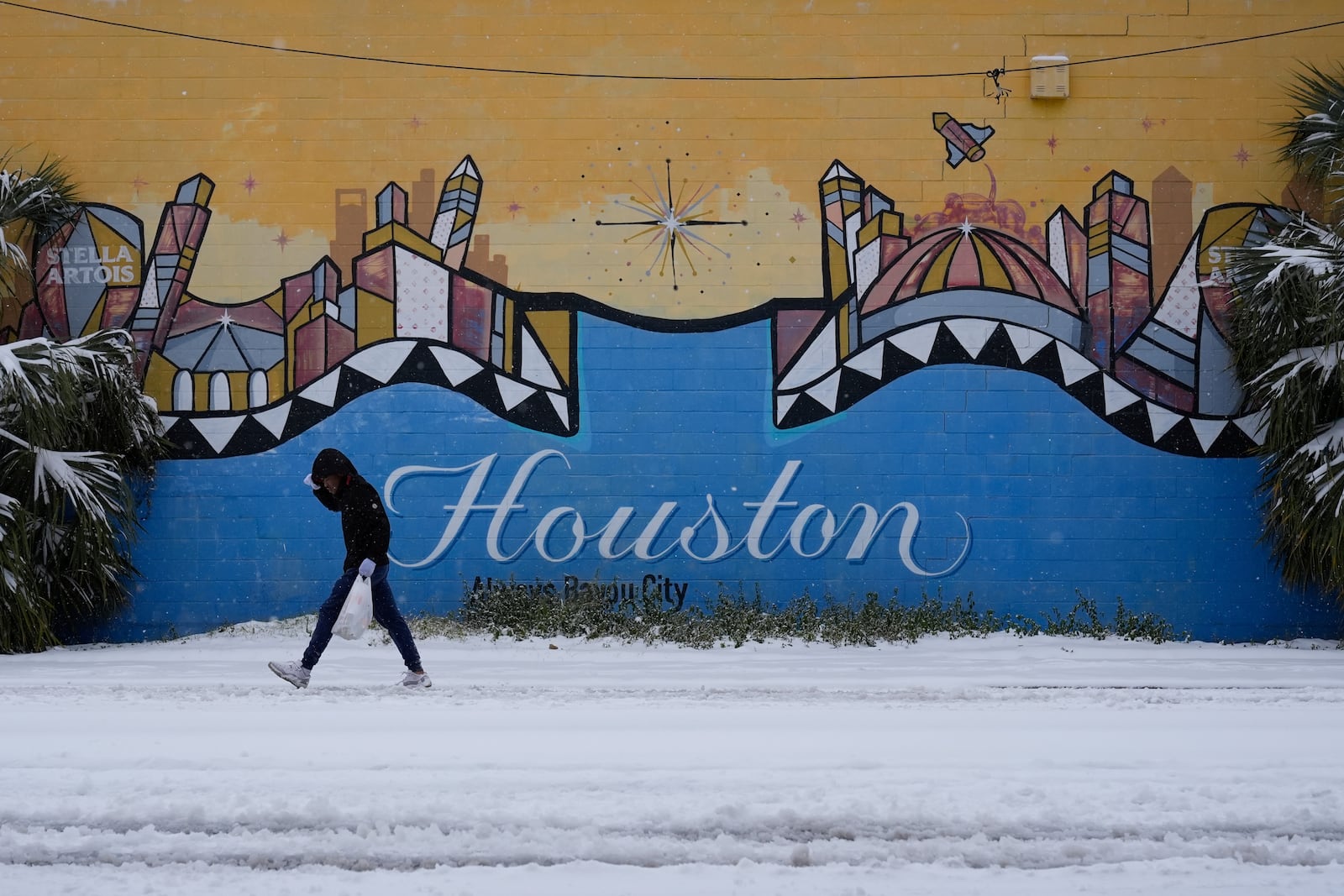 A person walks on a snow covered street Tuesday, Jan. 21, 2025, in Houston. (AP Photo/Ashley Landis)