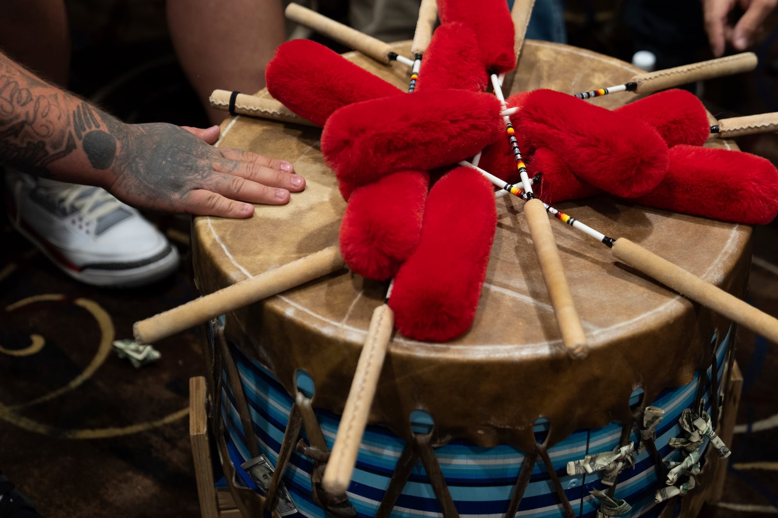 Taylor Hawk, a member of the Warrior Society drum group, touches the drum after playing during a powwow at Chinook Winds Casino Resort, Saturday, Nov. 16, 2024, in Lincoln City, Ore. (AP Photo/Jenny Kane)