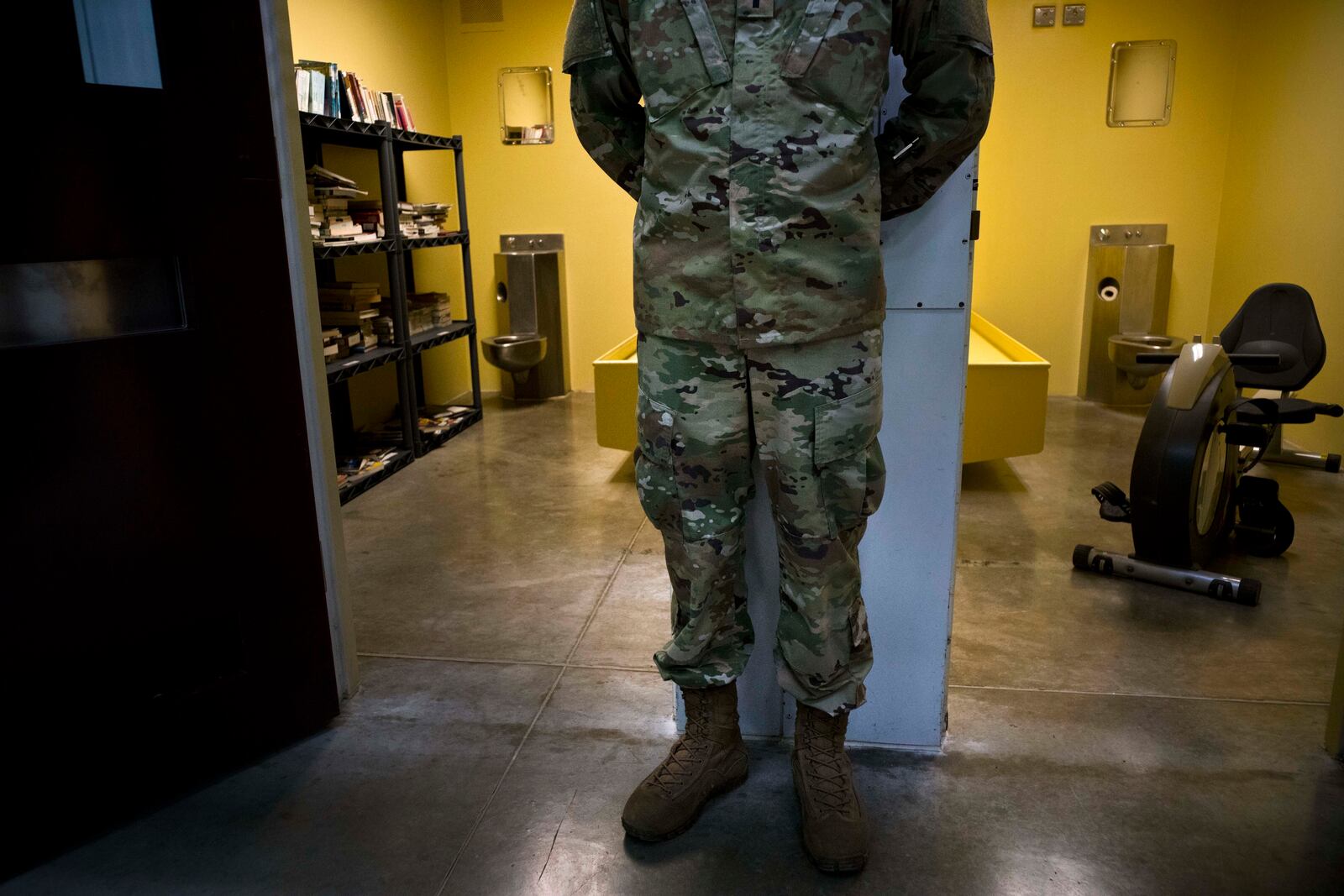 FILE - In this photo reviewed by U.S. military officials, a U.S. soldier stands between two cells, one used as a library and the other a gym, inside the Camp VI detention facility at the Guantanamo Bay U.S. naval base in Cuba, June 6, 2018. (AP Photo/Ramon Espinosa, File)