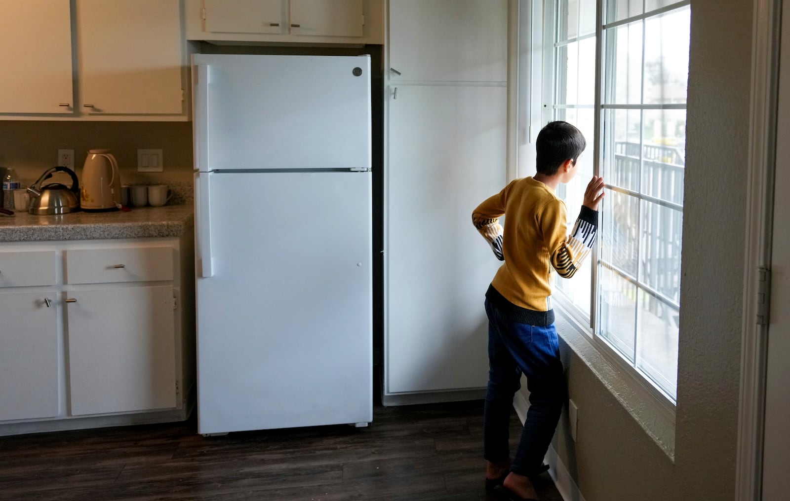 Mohammad Samir Osmani, looks out a window of his families new home provided by the No One Left Behind Organization, in Rancho Cordova, Calif., Wednesday, March 12, 2025. (AP Photo/Rich Pedroncelli)