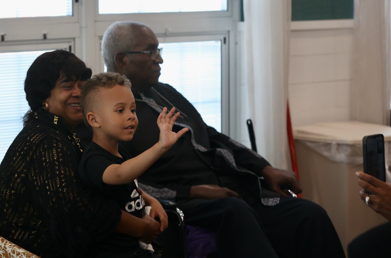 True Cooper, the grandson of Michael Cooper Sr., of Springfield, waves to the crowd as he sits on his grandma Tobi Cooper's lap during a service held in Cooper Sr.'s honor on Sunday, May 21, at Trinity Community in Fairborn. David Jablonski/Staff