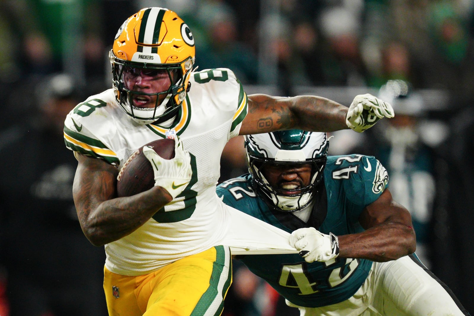 Green Bay Packers running back Josh Jacobs (8) runs the ball as Philadelphia Eagles linebacker Oren Burks (42) pulls his shirt during the second half of an NFL wild-card playoff football game Sunday, Jan. 12, 2025, in Philadelphia. (AP Photo/Derik Hamilton)