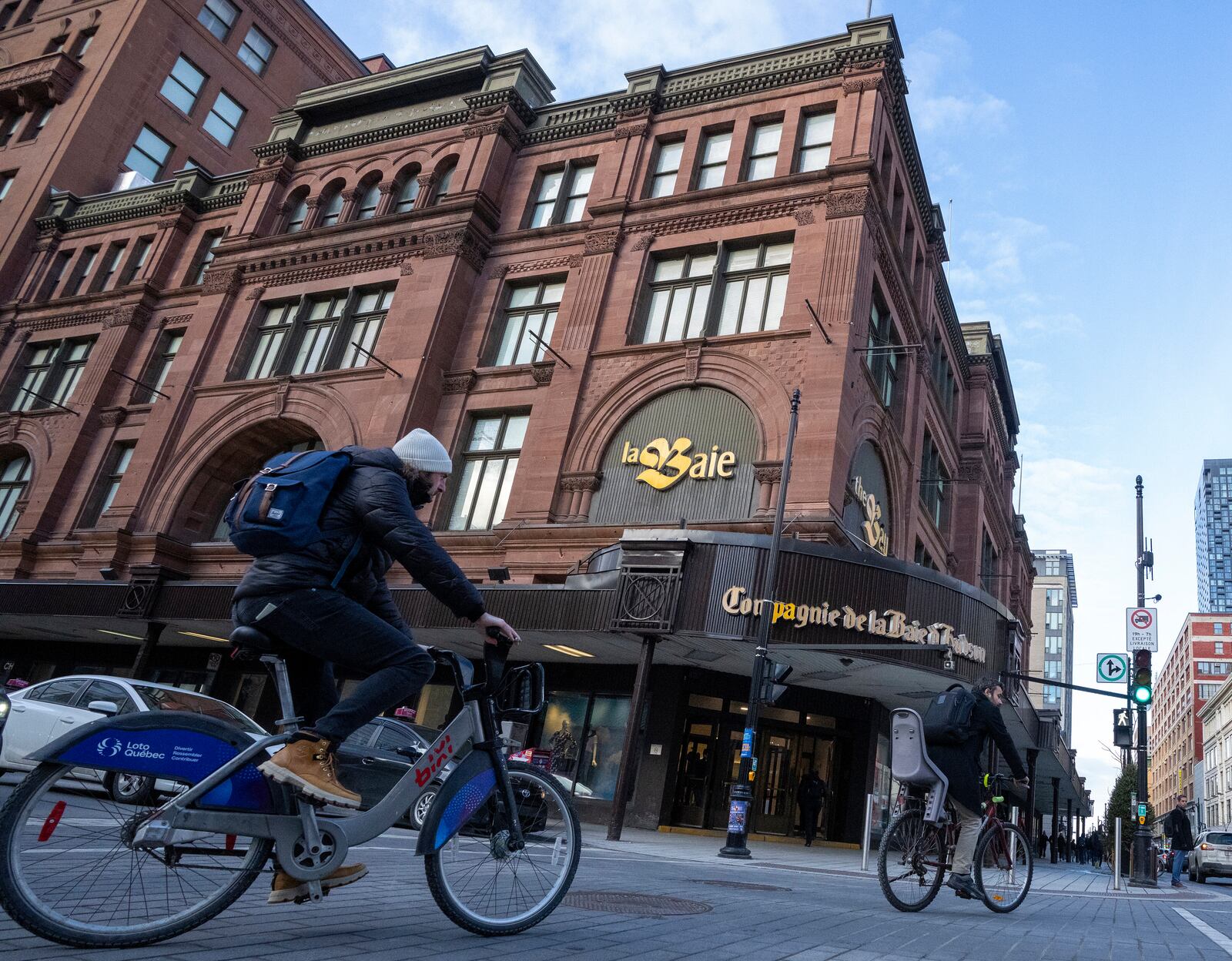 People cycle past the Hudson's Bay department store in downtown Montreal, Monday, March 17, 2025. (Christinne Muschi/The Canadian Press via AP)