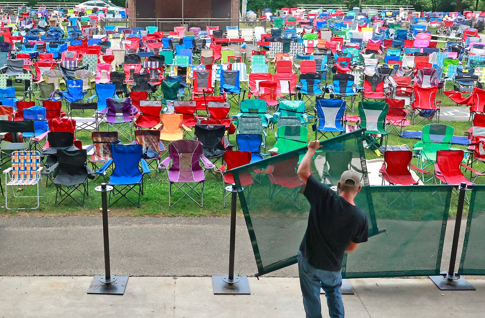 Brandon Chance sets up the barrier for the paid seating for Wednesday evening's Summer Arts Festival Performance of Resurrection: A Journey Tribute at the Veteran's Park Amphitheater. BILL LACKEY/STAFF