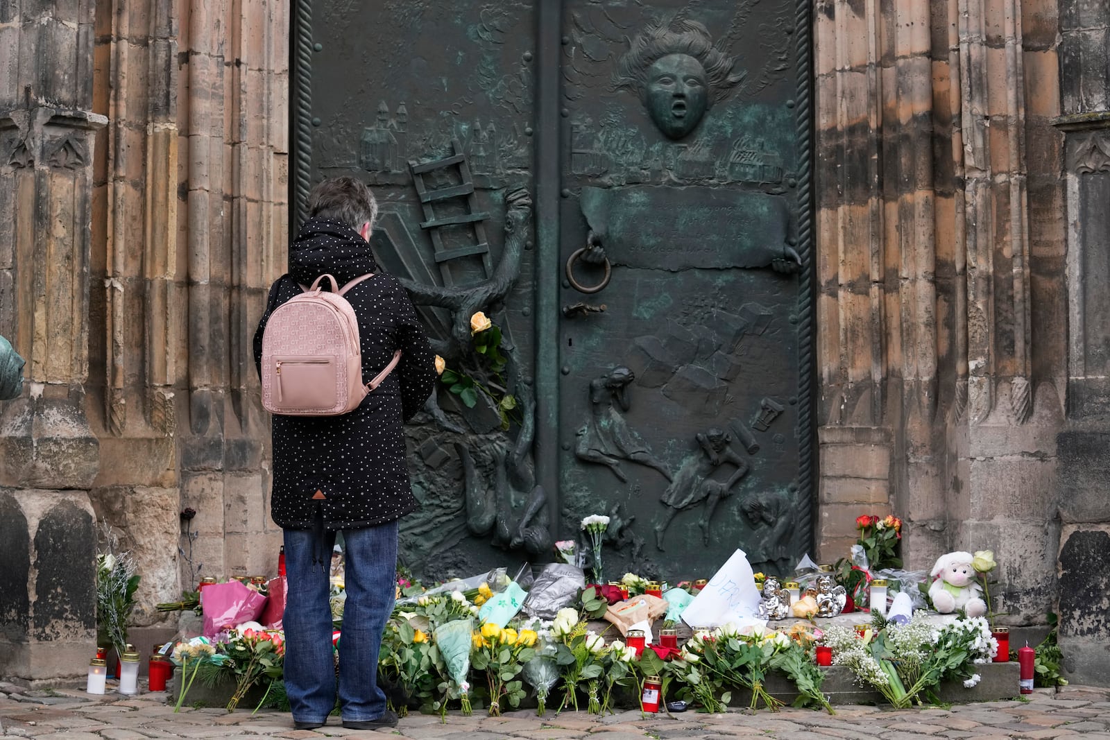 A person stands by flowers and candles placed outside St. John's Church near a Christmas Market, where a car drove into a crowd on Friday evening, in Magdeburg, Germany, Saturday, Dec. 21, 2024. (AP Photo/Ebrahim Noroozi)