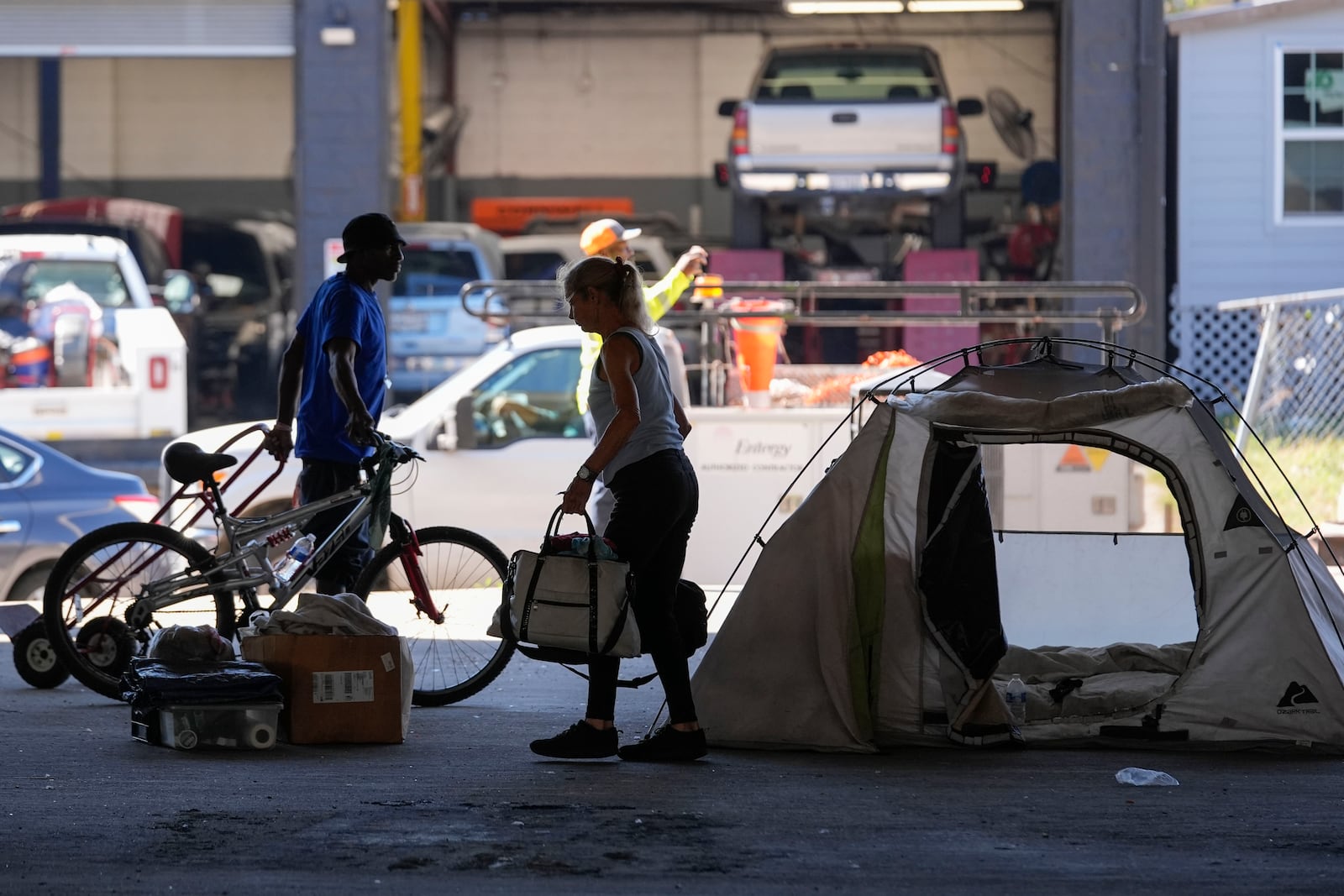 People living in a homeless encampment pick up belongings after Louisiana State police gave instructions for them to move to a different pre-designated location as they perform a sweep in advance of a Taylor Swift concert in New Orleans, Wednesday, Oct. 23, 2024. (AP Photo/Gerald Herbert)