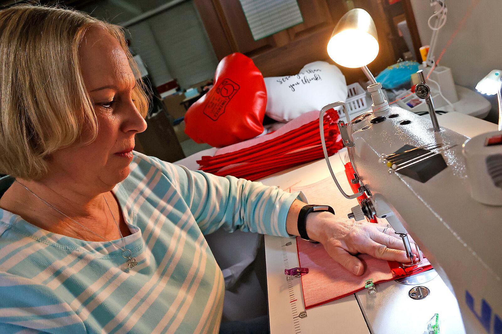 Lynette Evans makes one of the heart pillows, which help people who have had open heart surgery, Wednesday, April 12, 2023 in her basement workshop. BILL LACKEY/STAFF