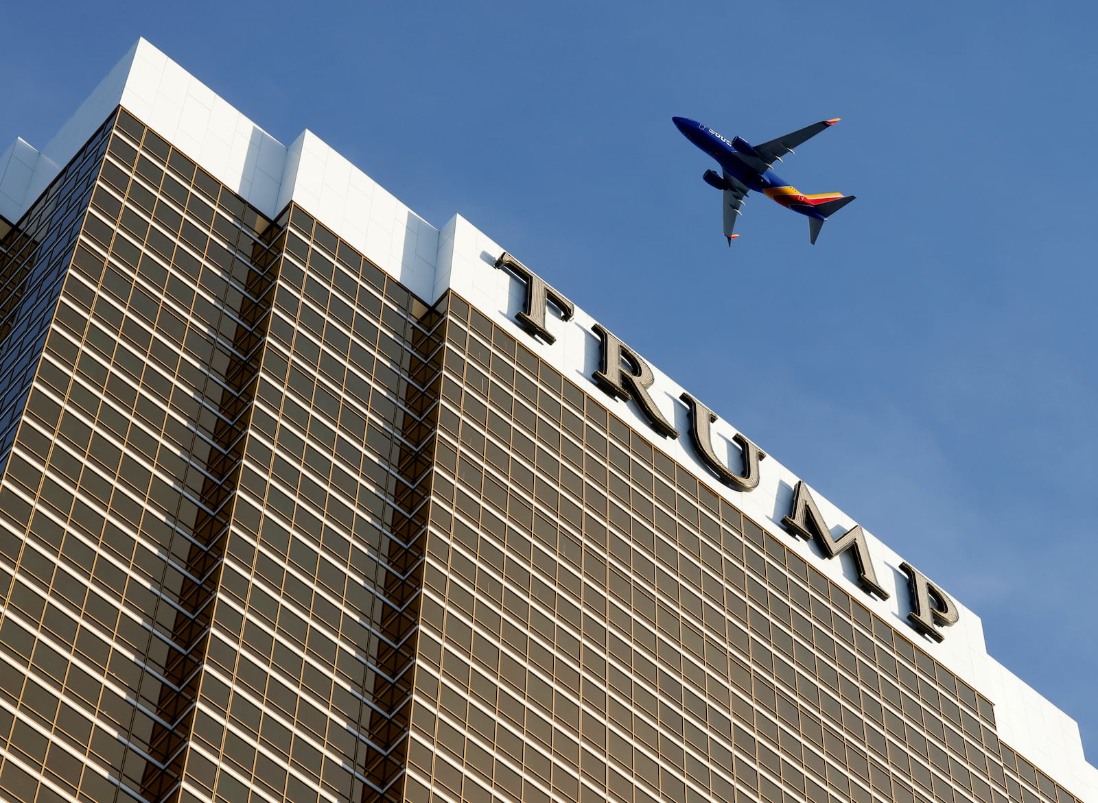 An airplane flies over Trump International Hotel, on Thursday, Jan. 2, 2025, in Las Vegas. (Bizuayehu Tesfaye/Las Vegas Review-Journal via AP)