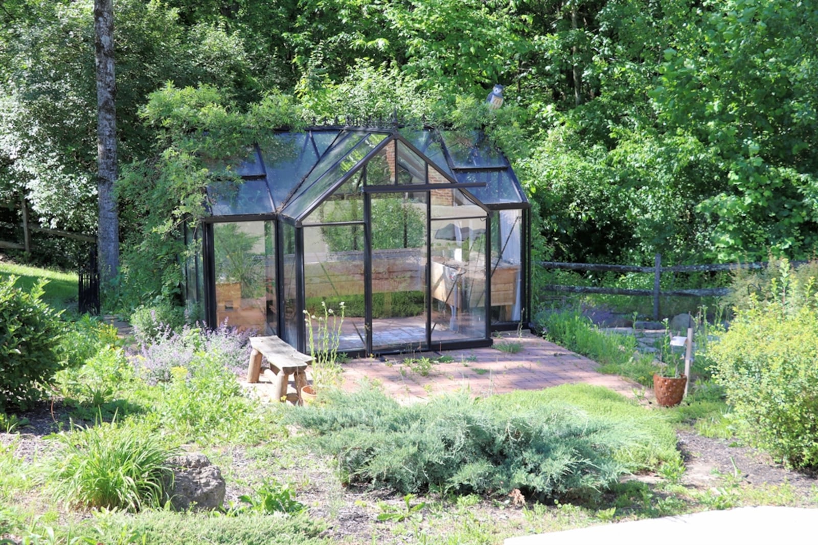 The greenhouse features tempered-glass panels, a paver brick floor, potting benches and an extended paver patio.