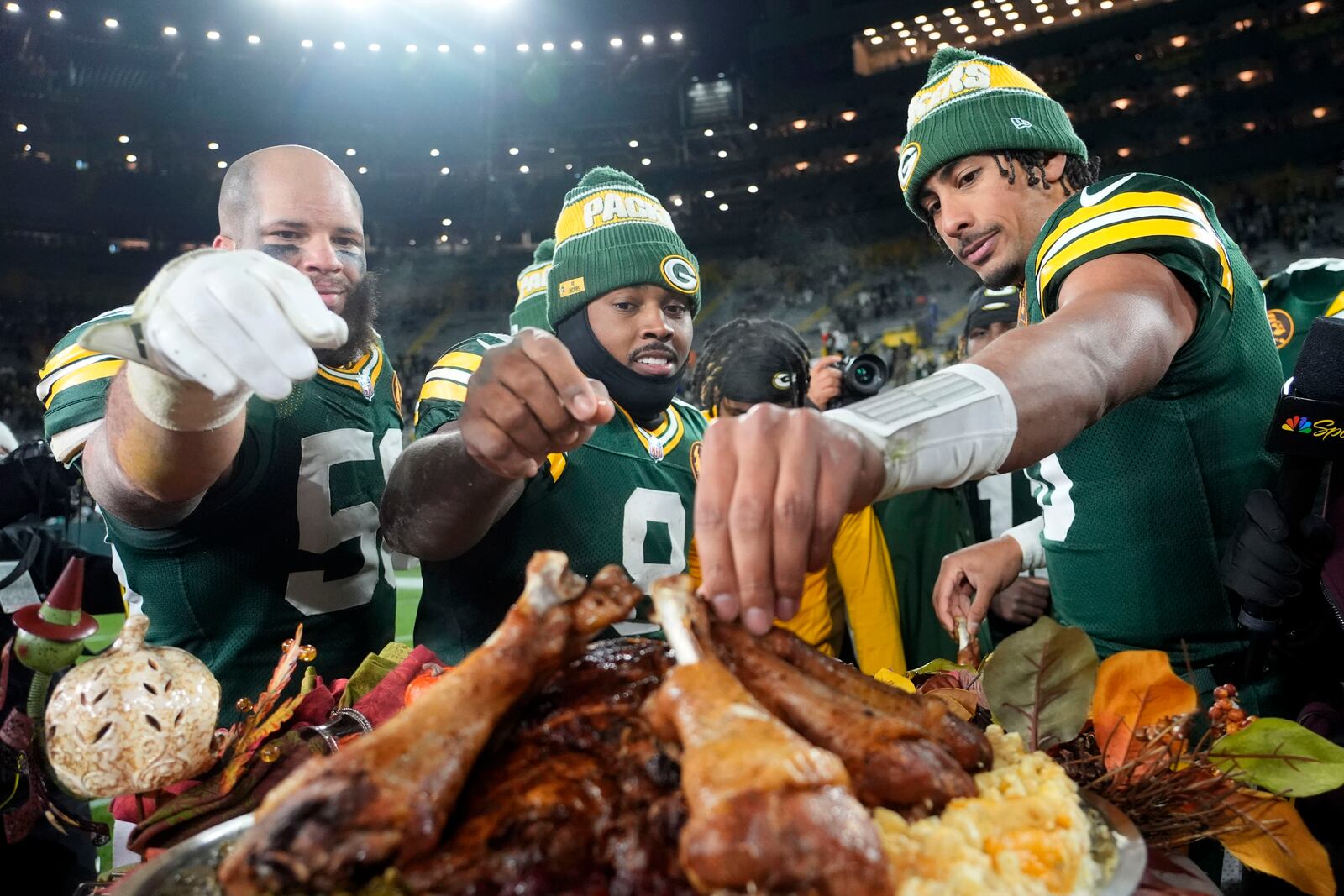 Green Bay Packers linebacker Isaiah McDuffie, from left, running back Josh Jacobs and quarterback Jordan Love eat turkey legs after an NFL football game against the Miami Dolphins Thursday, Nov. 28, 2024, in Green Bay, Wis. (AP Photo/Morry Gash)