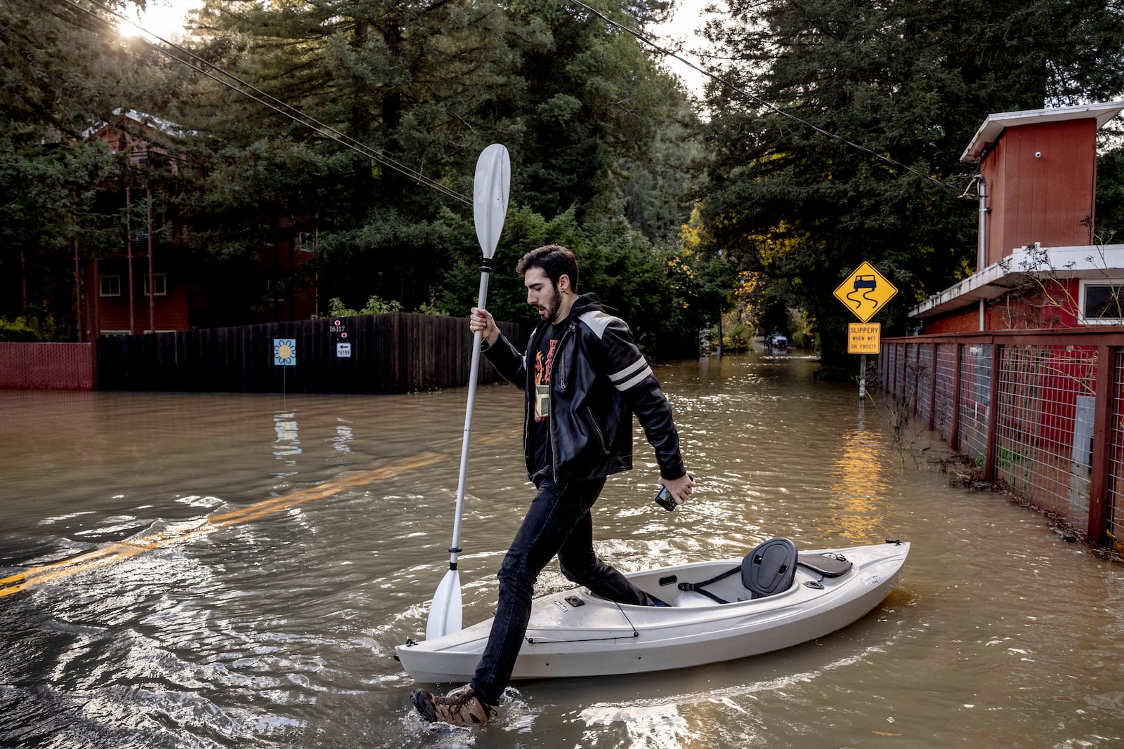 FILE - Tristan Millstone reacts as he steps in water after kayaking across a flooded section of Neely Road to buy groceries after a major storm in Guerneville, Calif., Saturday, Nov. 23, 2024. (Stephen Lam/San Francisco Chronicle via AP, file)