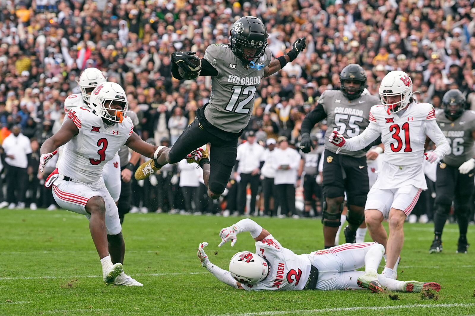 FILE - Colorado wide receiver Travis Hunter (12) flies in for a touchdown past, from left, Utah linebacker Johnathan Hall, cornerback Smith Snowden and safety Nate Ritchie during the second half of an NCAA college football game Saturday, Nov. 16, 2024, in Boulder, Colo. (AP Photo/David Zalubowski, File)