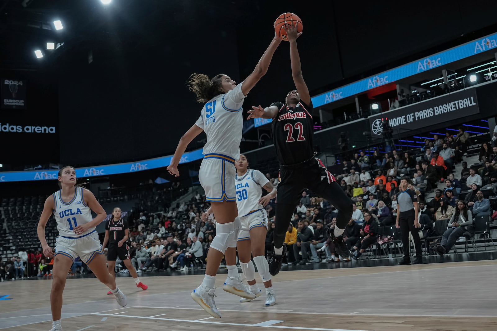 UCLA center Lauren Betts and Louisville's guard Tajianna Roberts (22) battle for the ball during an NCAA college basketball game Monday, Nov. 4, 2024, in Paris, France. (AP Photo/Aurelien Morissard)