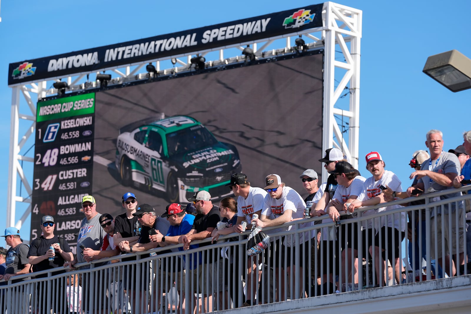 Fans watch a practice session for the NASCAR Daytona 500 auto race from the rooftop of the Fan Zone in front of a video screen at Daytona International Speedway, Saturday, July 15, 2025, in Daytona Beach, Fla. (AP Photo/John Raoux)