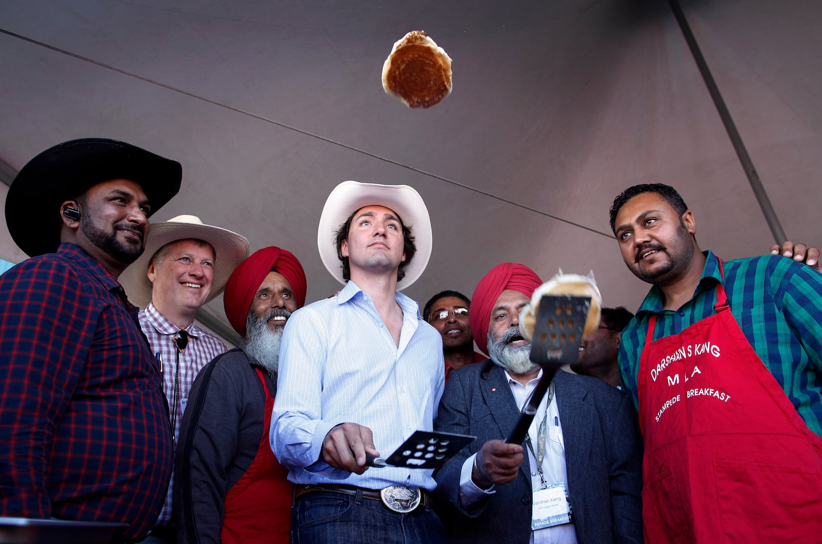 FILE - Liberal leader Justin Trudeau, center, flips pancakes at a Stampede breakfast in Calgary, Alta., on July 7, 2013. (Jeff McIntosh/The Canadian Press via AP, File)