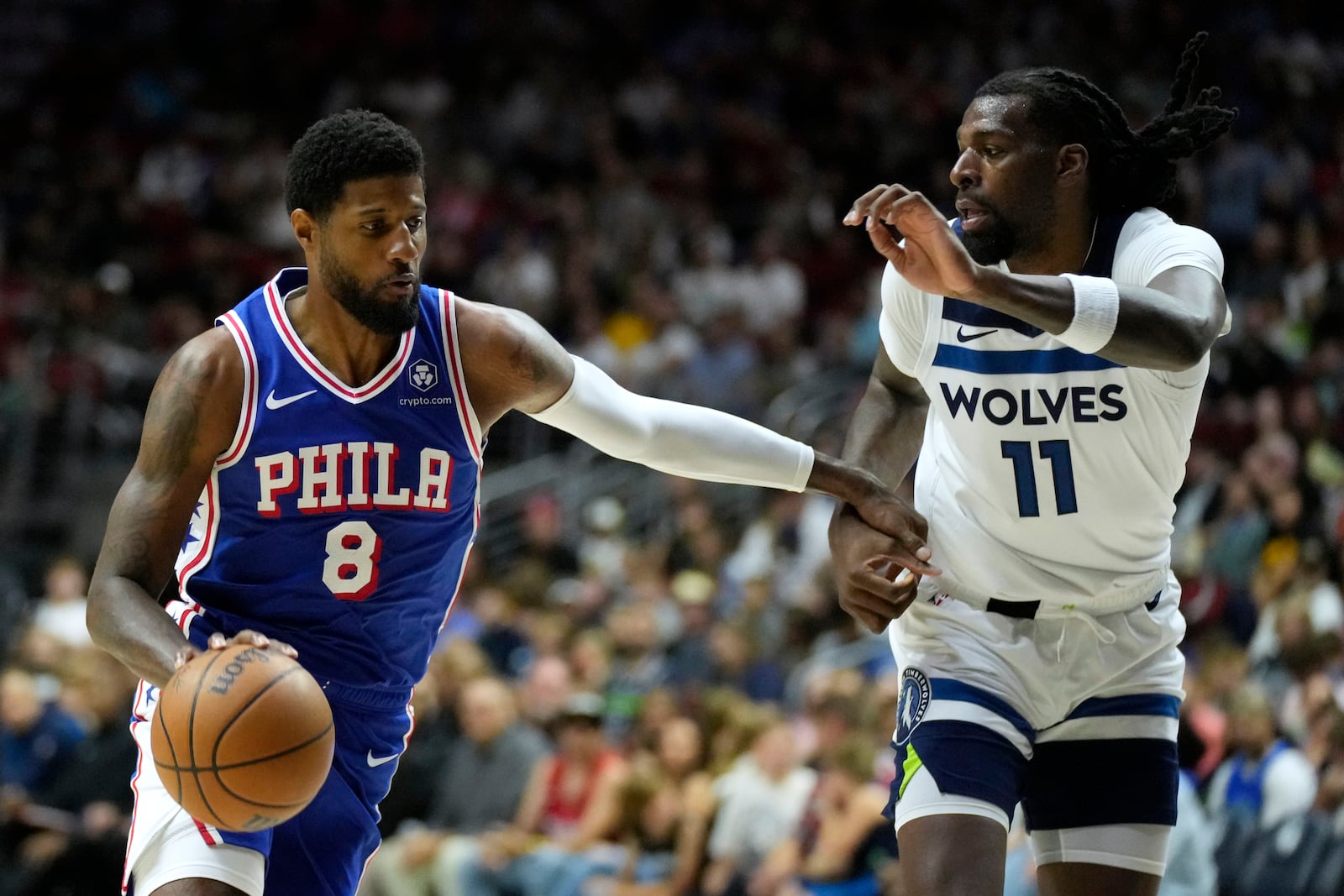 Philadelphia 76ers forward Paul George (8) drives to the basket past Minnesota Timberwolves center Naz Reid (11) during the first half of an NBA preseason basketball game, Friday, Oct. 11, 2024, in Des Moines, Iowa. (AP Photo/Charlie Neibergall)