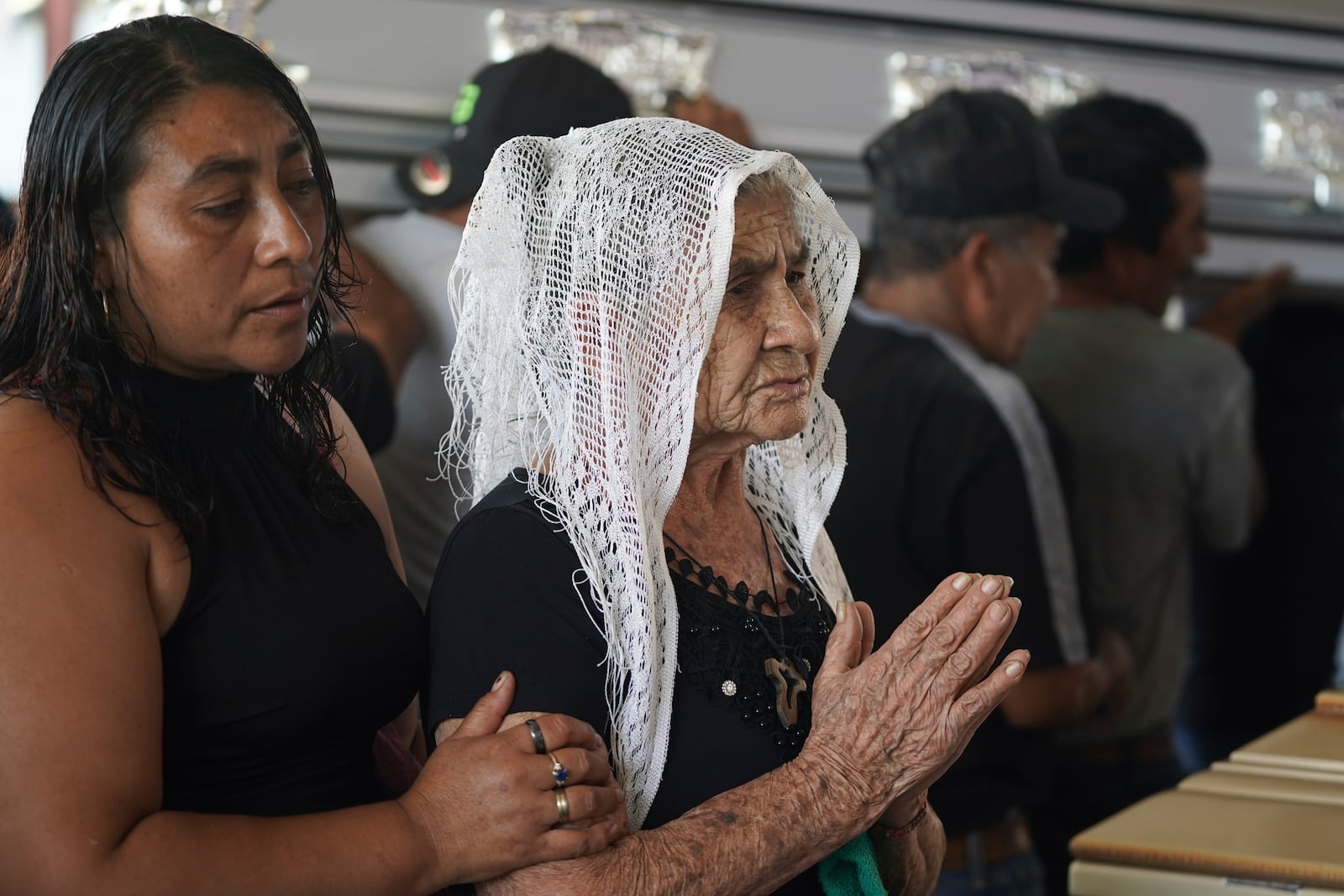 Mourners pay their final respects to the victims of a bus crash at a funeral service in Santo Domingo Los Ocotes, Guatemala, Tuesday, Feb. 11, 2025. Dozens of passengers died after their bus plunged into a gorge and landed under a bridge on Feb. 10 on the outskirts of Guatemalan capital. (AP Photo/Moises Castillo)